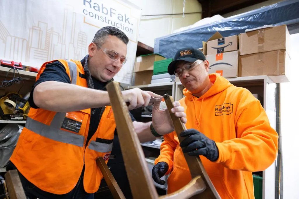 Roman Dimaksyan (left) teaches employee Rob Haidarali how to restore a chair in the shop at RabFak Construction on Friday, Jan. 17, 2025, in Omaha. Dimaksyan prides himself on training employees, many of whom are immigrants, but then says he needs replacements when they grow skills and confidence and start their own businesses.<br />(Rebecca S. Gratz / Flatwater Free Press)