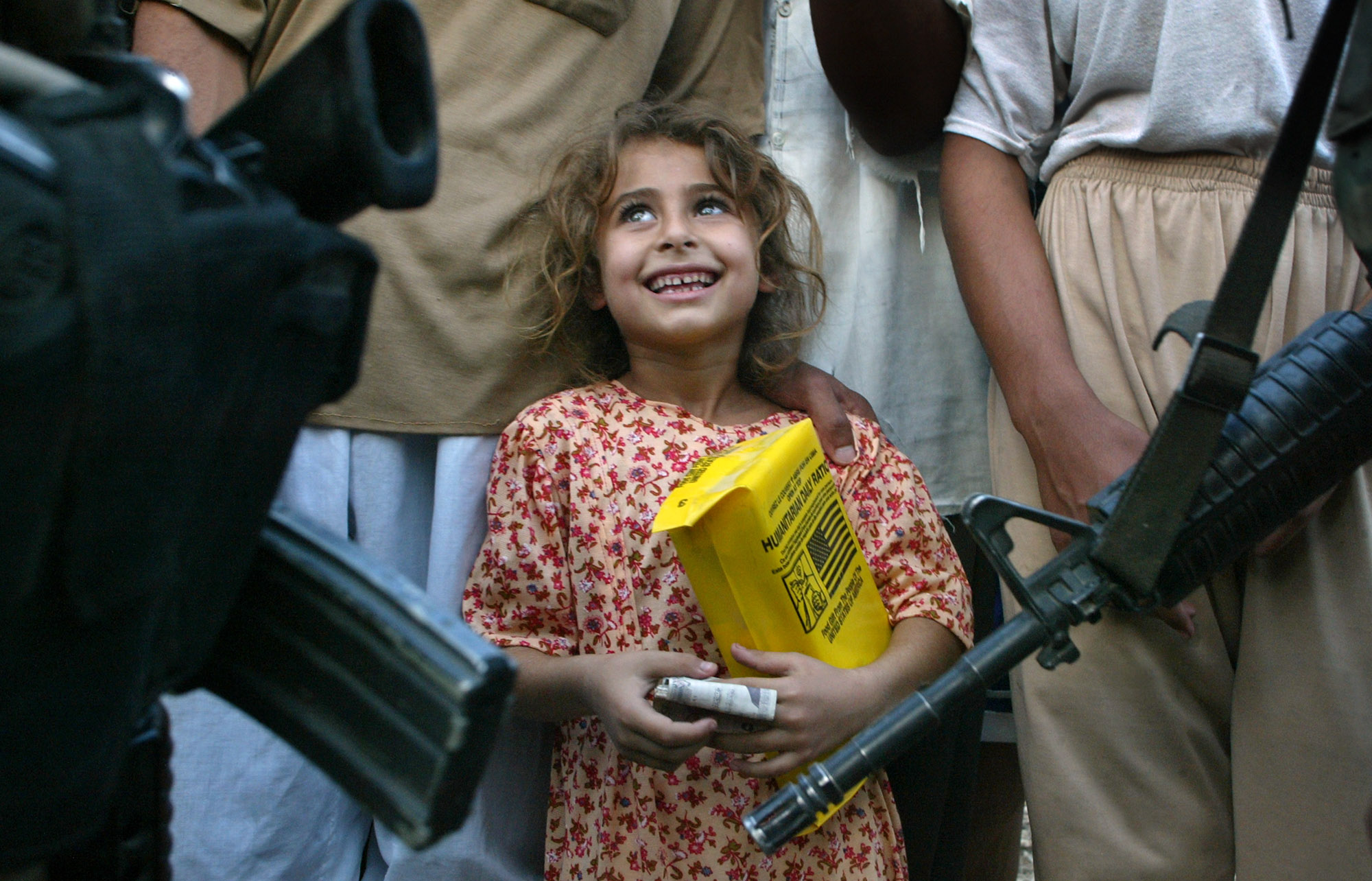 An Iraqi girl holds a packet of humanitarian food aid given by U.S. Army medics from the 26 Forward Support Battalion in the countryside outside Fallujah, Iraq Wednesday, July 9, 2003.<br />(John Moore / AP Photo)