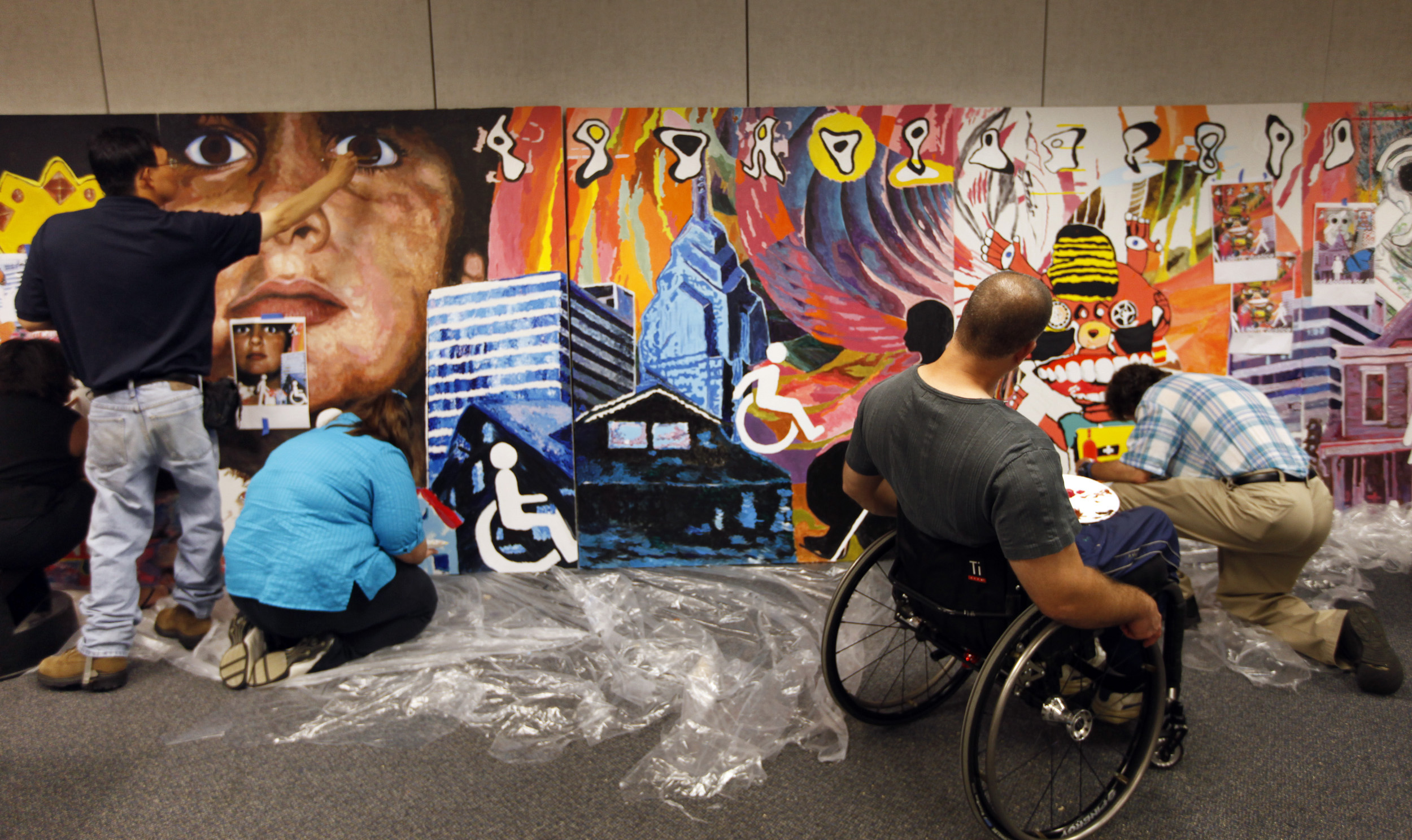 This inclusive community mural project celebrated the 20th anniversary of the Americans with Disabilities Act by creating a mural that integrated the artworks submitted by 13 Ohio artists with disabilities. Prof. Kong Ho (left) was the leading artist and worked with the participating Ohio artists during a 3-day intensive mural painting workshop in producing this 6-foot by 30-foot wide mural.<br />(Shari Lewis / The Columbus Dispatch via AP)
