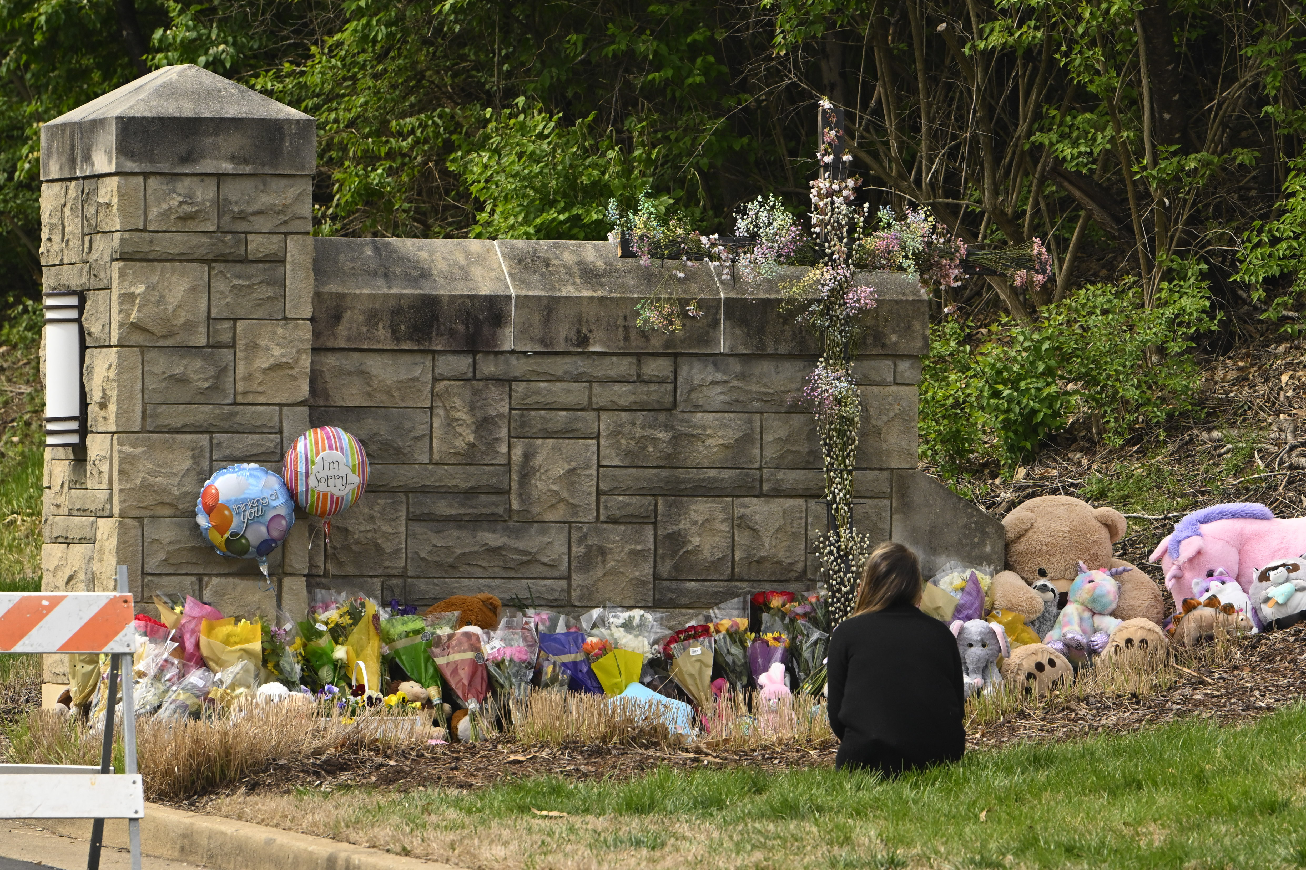 A person kneels in front of an entry to Covenant School which has become a memorial for shooting victims, Tuesday, March 28, 2023, in Nashville, Tenn. Six people were killed at the small, private Christian school last Monday after a shooter opened fire inside the 200-student school. (John Amis / AP Photo)