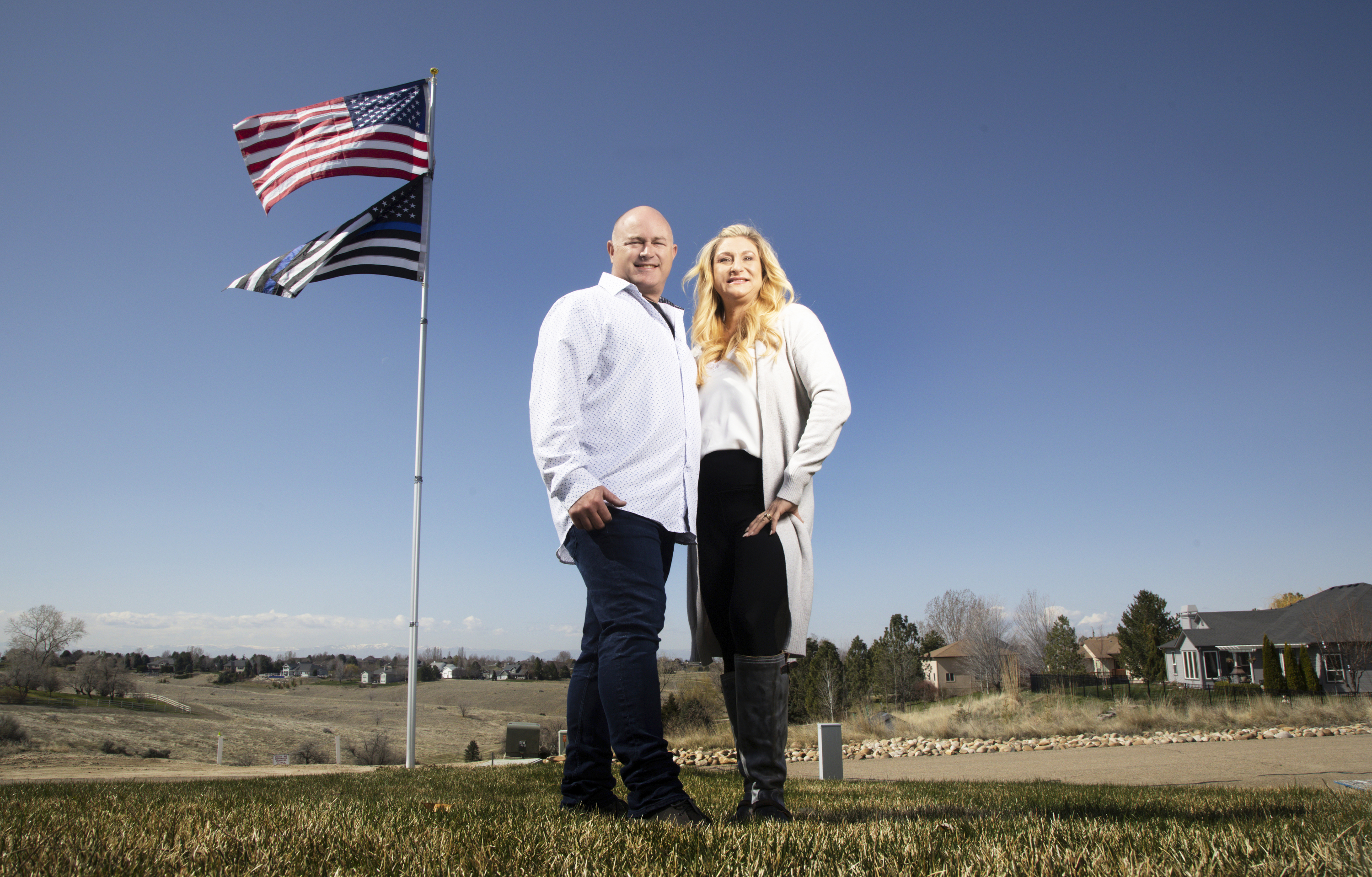 Jennifer and Tim Kohl poses for a photo in their front yard with the American flag and a thin blue line flag in Star, Idaho, on April 14, 2023. The retired LA police officer would have never dared to put up the thin blue line flag at his home in California. The couple recently moved to Idaho from the Los Angeles area. Americans are segregating by their politics at a rapid clip, helping fuel the greatest divide between the states in modern history. (Kyle Green / AP Photo)