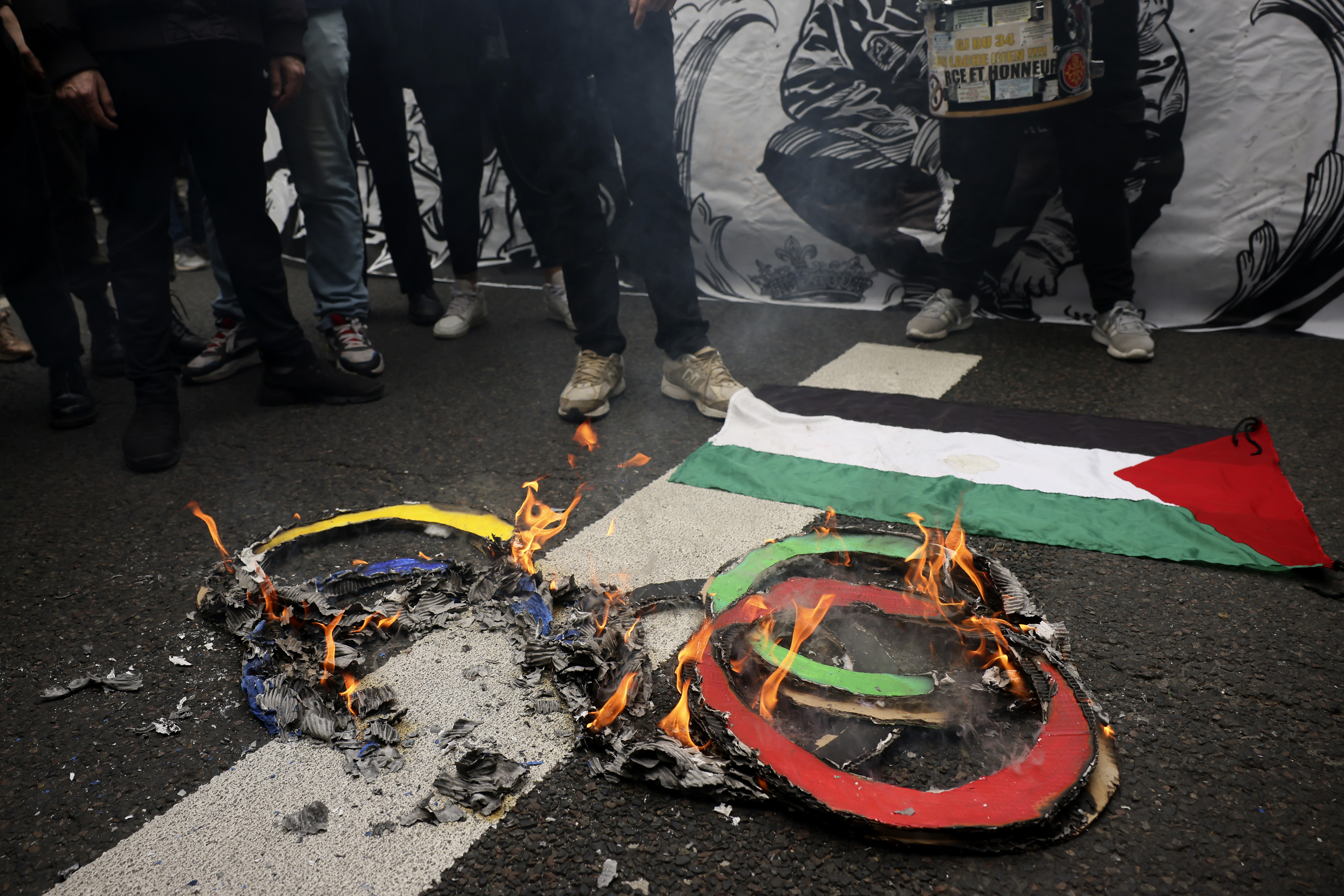 Protesters burn olympic rings on the pavement near a Palestinian flag during the May Day demonstration, Wednesday, May 1, 2024 in Paris.<br />(Thomas Padilla / AP Photo)