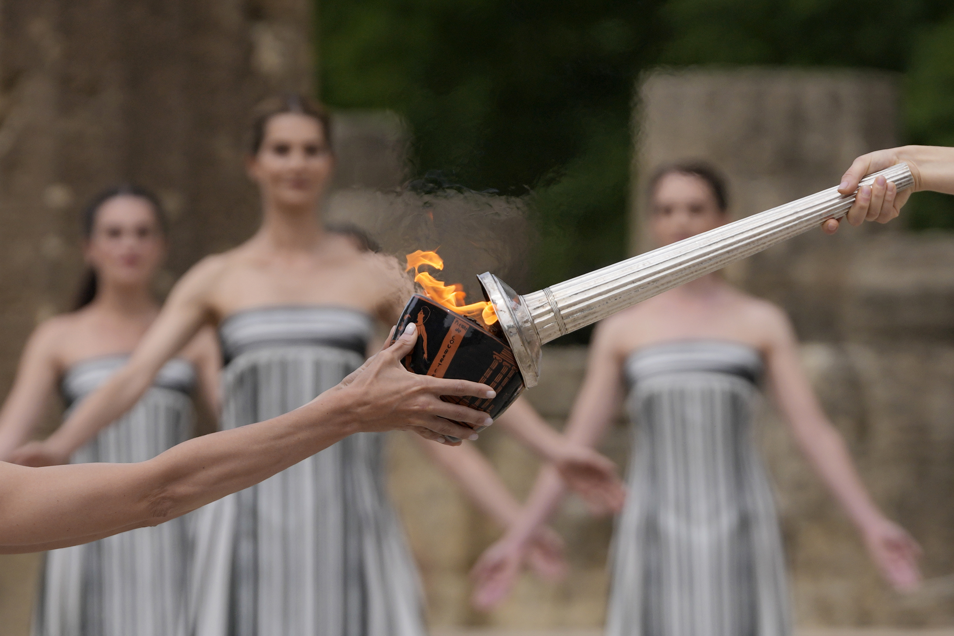 Actress Mary Mina, playing high priestess, right, lights a torch during the official ceremony of the flame lighting for the Paris Olympics, at the Ancient Olympia site, Greece, April 16, 2024.<br />(Thanassis Stavrakis / AP Photo)