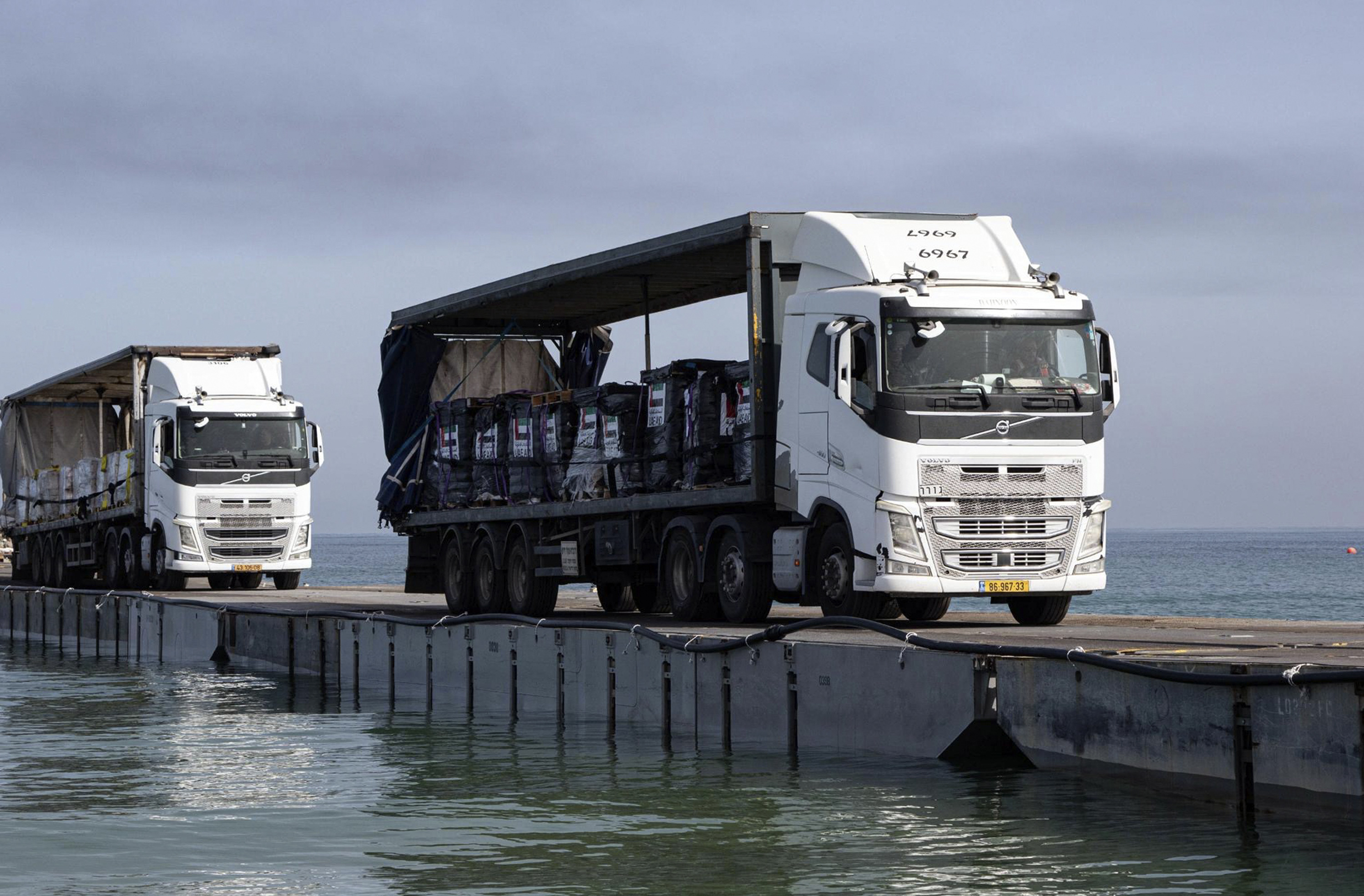 This image provided by the U.S. Army shows trucks loaded with humanitarian aid from the United Arab Emirates and the United States Agency for International Development cross the Trident Pier before arriving on the beach on the Gaza Strip, May 17, 2024.<br />(Staff Sgt. Malcolm Cohens-Ashley / U.S. Army / AP Photo)