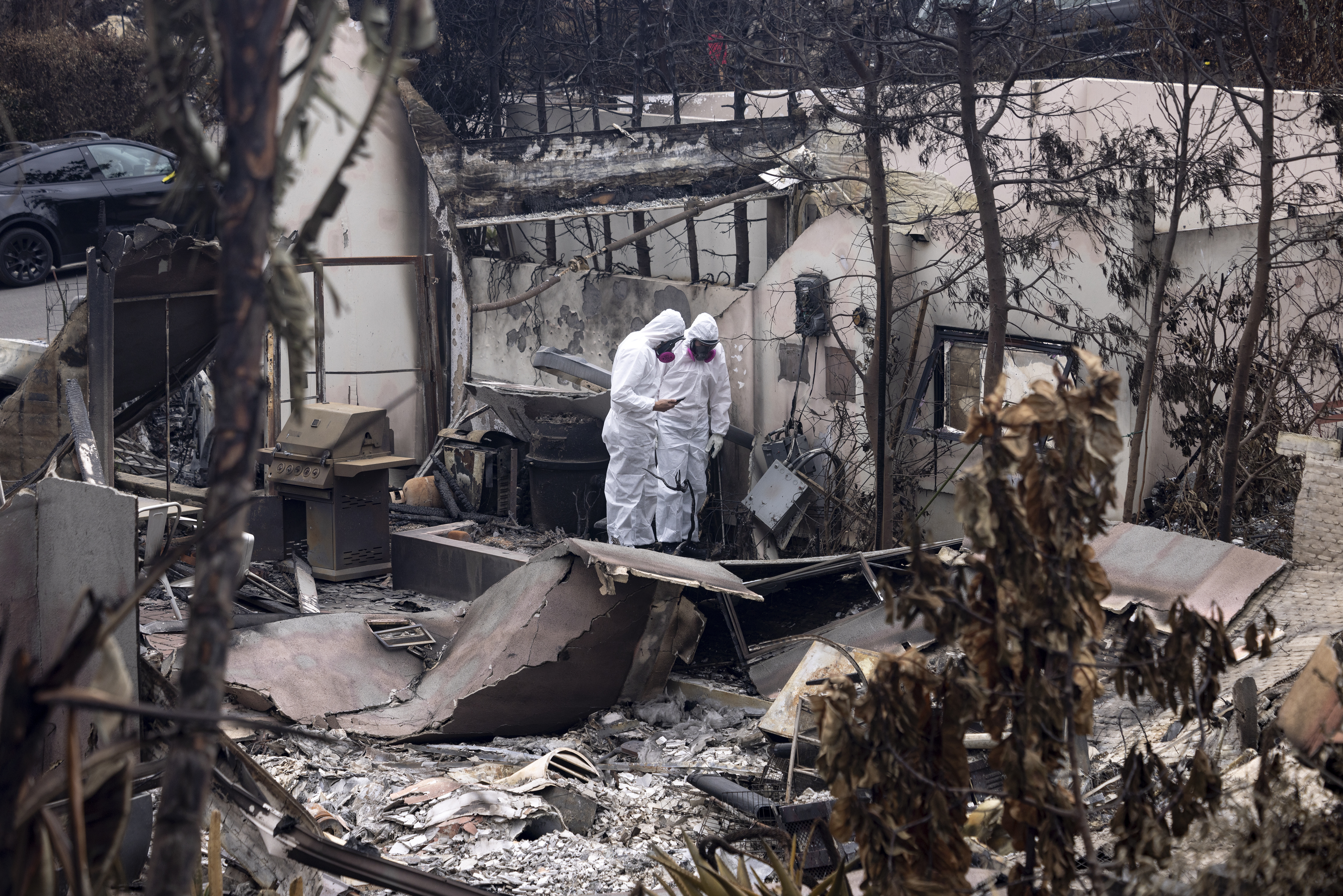 Homeowners dressed in full body protective gear walk among the rubbles of their house destroyed by the Palisades Fire, in the Pacific Palisades neighborhood of Los Angeles, Calif., Saturday, Jan. 25, 2025.<br />(Etienne Laurent / AP Photo)