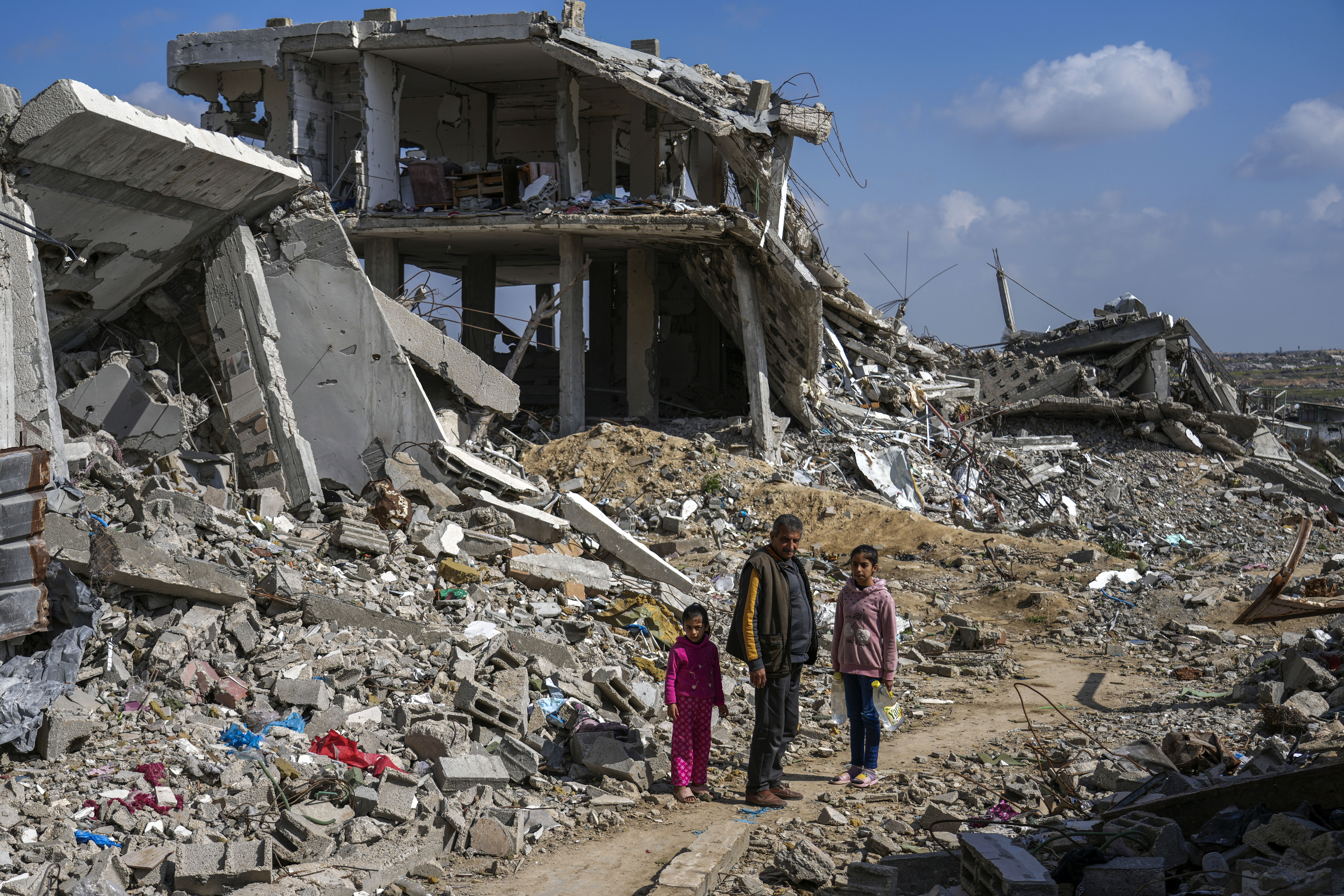 A Palestinian man and two girls stand a mid of the rubble of homes, destroyed by the Israeli army&#039;s air and ground offensive against Hamas in Bureij refugee camp, central Gaza Strip, Monday, Feb. 17, 2025.<br />(Abdel Kareem Hana / AP Photo)
