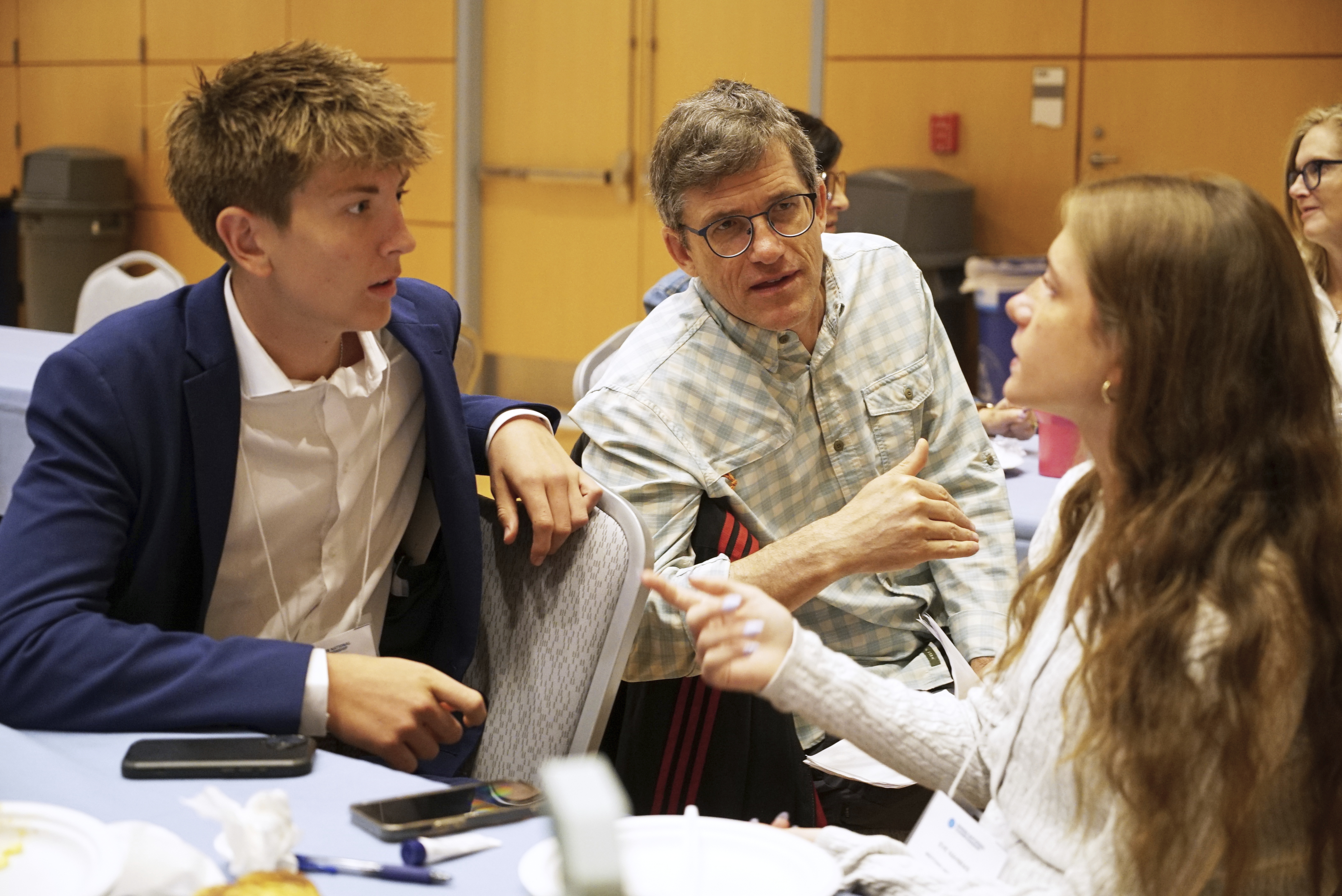 Midtown High School Ethics Bowl teammates Eric Snell (left) and Eve Nahmias speak with coach Eddy Nahmias, Eve&#039;s father, in between rounds of the National High School Ethics Bowl in Chapel Hill, N.C., on Sunday, April 13, 2025.<br />(Allen G. Breed / AP Photo)