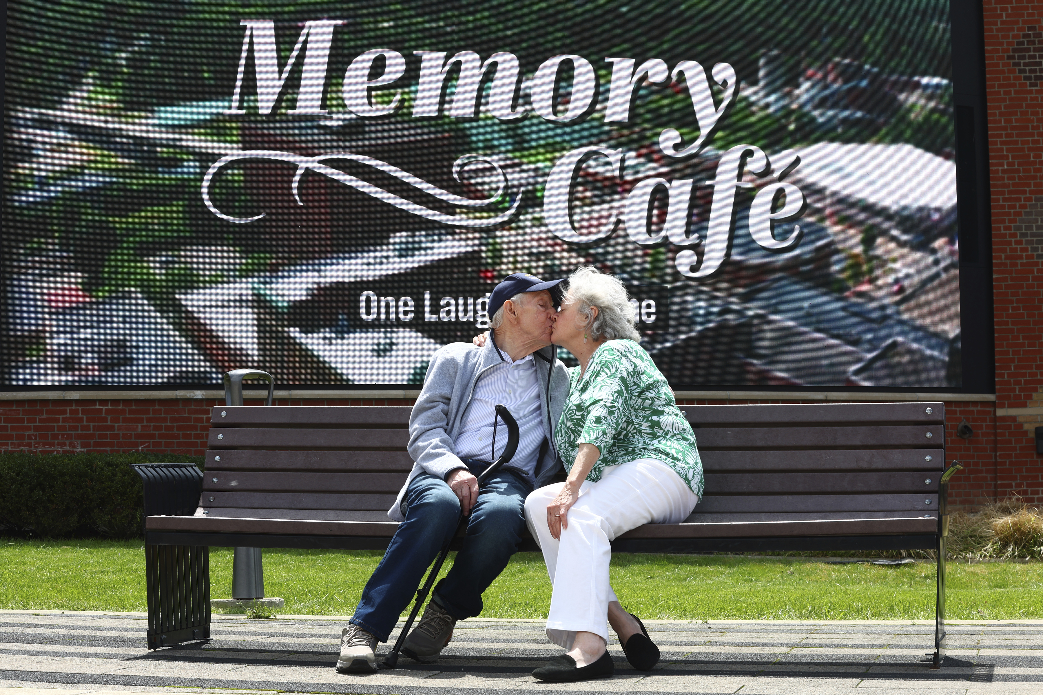 Mario and Gail Cirasunda share a kiss on a bench following a Memory Cafe event at the National Comedy Center.<br />(Jeffrey T. Barnes / AP Photo)