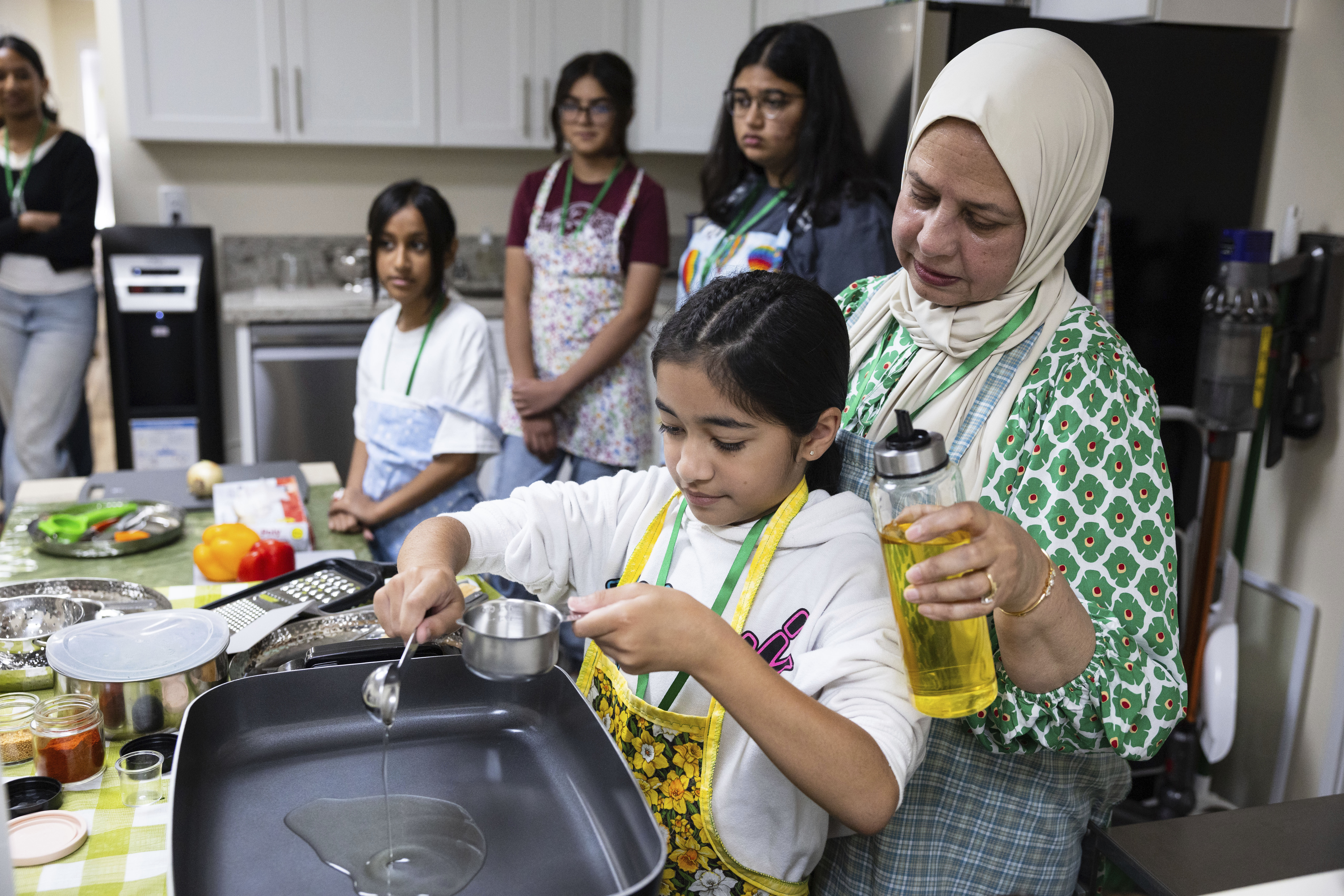 Shameem Syed helps student Zaaria Moosani during a cooking class at Olive Community Services, Tuesday, July 29, 2025, in Fullerton, Calif.<br />(Zoë Meyers / AP Photo)