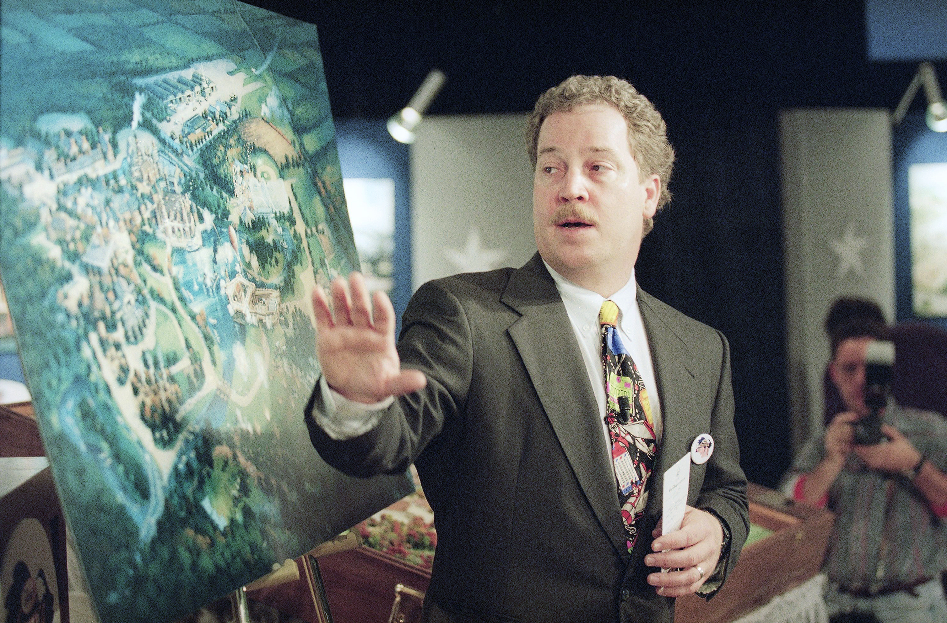 Bob Weis of the Walt Disney Company’s Imagineering Department, points to an artist rendering of the proposed Disney’s America theme park during a news conference in Manassas, Virginia, Nov. 11, 1993. The Disney company announced, it will build the theme park where visitors would relive great moments of history on a site in the rolling hills of the Civil War battlefield community.<br />(J. Scott Applewhite / AP Photo)
