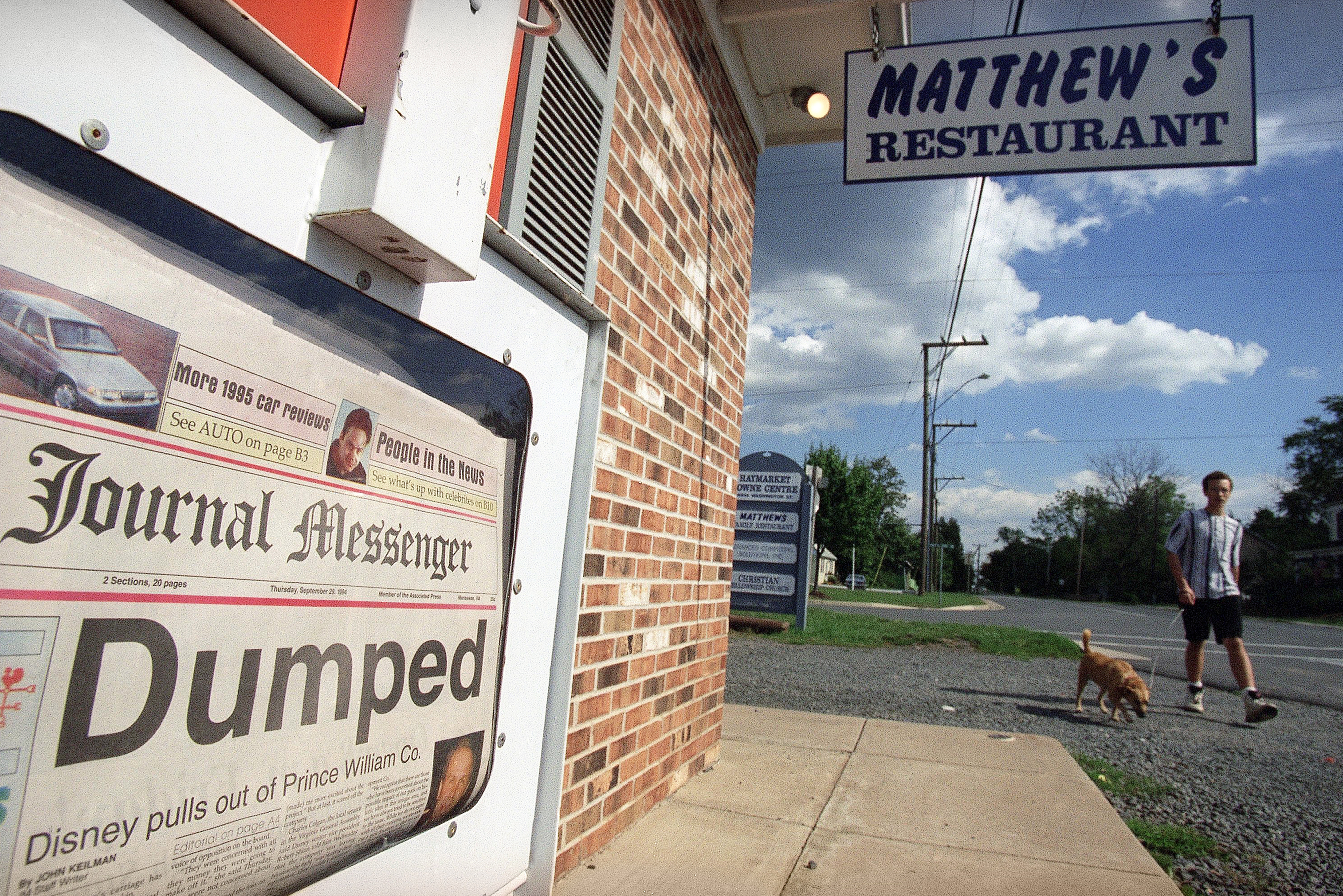 Jason Roberts, 14 walks his dog Windy down main street in Haymarket, Virginia, Sept. 29, 1994, past a Journal Messenger newspaper proclaiming “Dumped.” The Walt Disney company announced that it will abandon plans for an American history theme part in Haymarket.<br />(Joe Marquette / AP Photo)