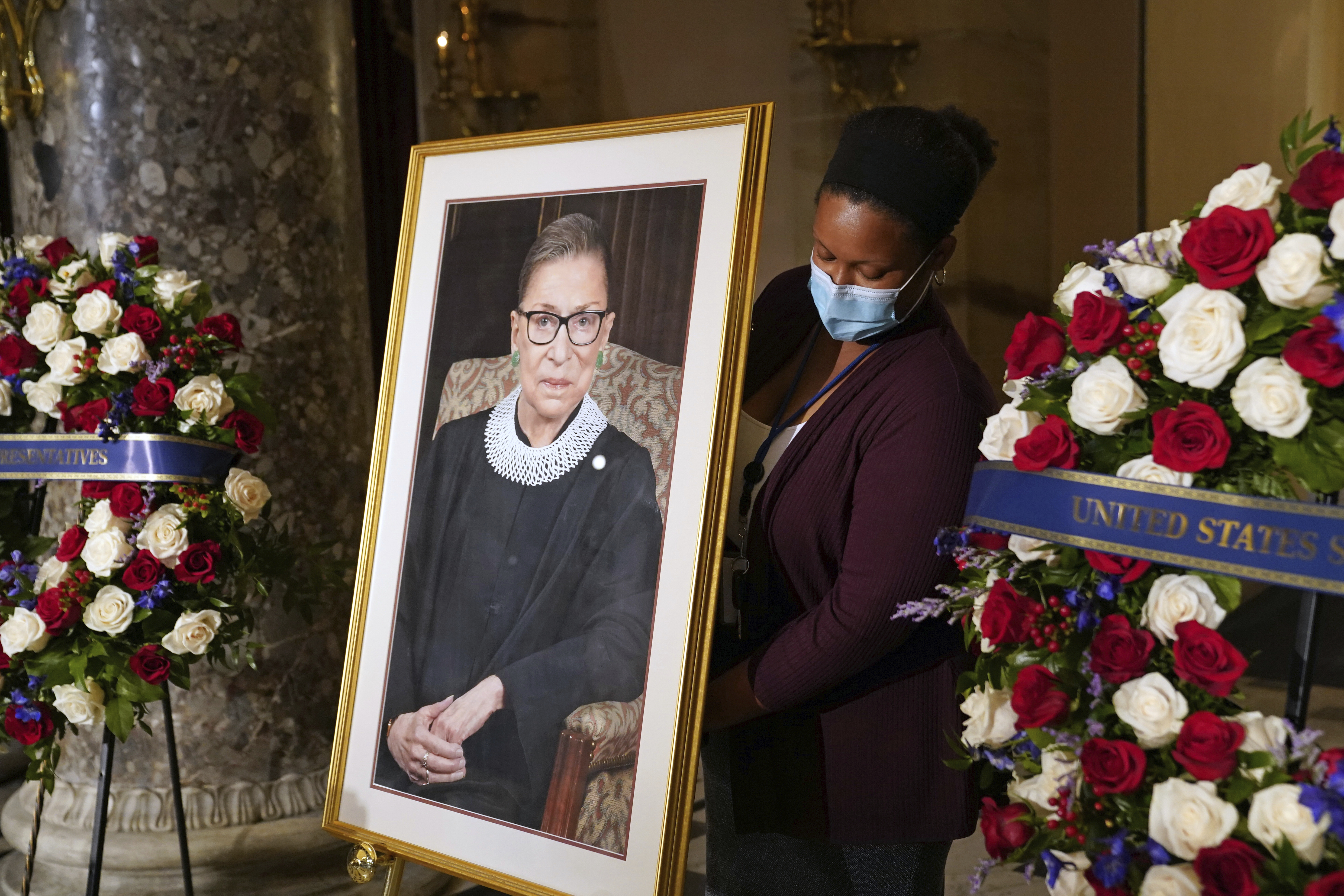 A staff member places a photo of Justice Ruth Bader Ginsburg before a ceremony for her to lie in state in Statuary Hall at the U.S. Capitol in Washington, Sept. 25, 2020.  (Erin Schaff / AP Photo)
