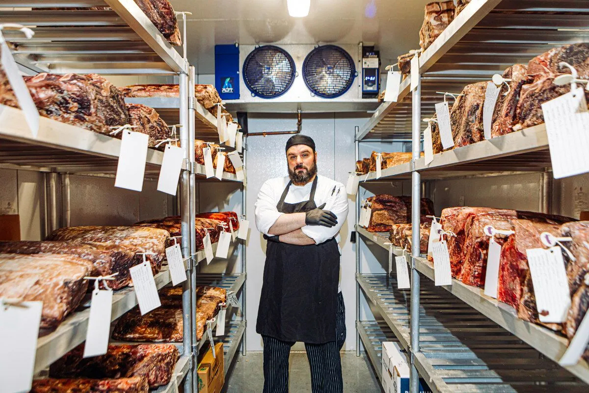 801 Chophouse Sous Chef Bryant Beach is pictured in the cooler where the restaurant dry ages beef.<br />(Joshua Foo / Flatwater Free Press)