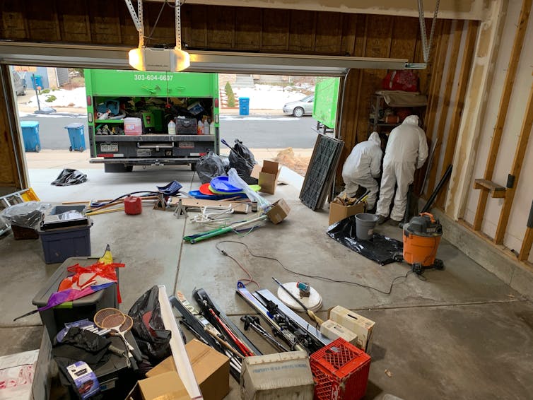 Remediation workers clean the garage of Gigi Yang, collaborator for the Marshall Fire Story Project. Due to concerns about toxins from smoke and ash residue in their homes, many residents opted for smoke remediation and deep cleaning of their homes.<br />(Courtesy of Gigi Yang, collaborator for the Marshall Fire Story Project)