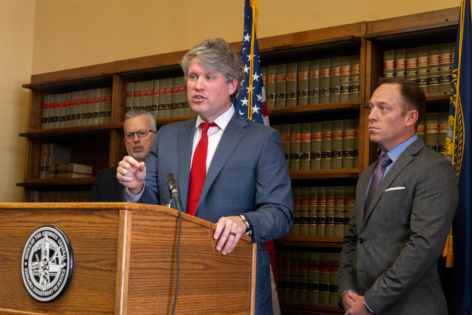 Nebraska Attorney General Mike Hilgers (center) announces a new antitrust lawsuit Tuesday, Nov. 19, 2024, against four major semitruck manufacturers and a national trade association. Also in attendence were Lincoln County Commissioner Chris Bruns (right), Kent Grisham (left) president and CEO of the Nebraska Trucking Association, and Lincoln County Commissioner Joe Hewgley (not photographed).<br />(Zach Wendling / Nebraska Examiner)