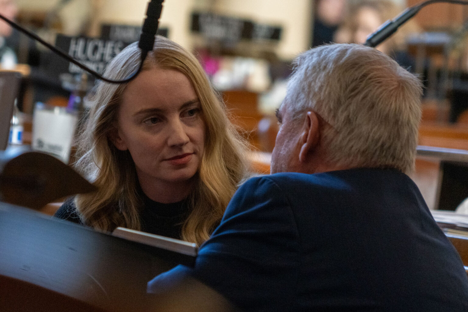 State Sen. Megan Hunt of Omaha listens to State Sen. Dave Murman of Glenvil kneeling at her desk on March 12, 2024.<br />(Zach Wendling / Nebraska Examiner)
