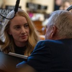 State Sen. Megan Hunt of Omaha listens to State Sen. Dave Murman of Glenvil kneeling at her desk on March 12, 2024. 
(Zach Wendling / Nebraska Examiner)