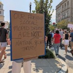 A demonstrator at a march on Sept. 6, 2025, protesting the Trump administration’s federalization of law enforcement and deployment of National Guard troops in Washington, D.C., held a sign on 16th Street NW defending local moped food delivery drivers. 
(Ashley Murray / States Newsroom)