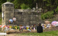 A person kneels in front of an entry to Covenant School which has become a memorial for shooting victims, Tuesday, March 28, 2023, in Nashville, Tenn. Six people were killed at the small, private Christian school last Monday after a shooter opened fire inside the 200-student school. (John Amis / AP Photo)