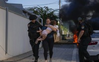 Israeli police officers evacuate a woman and a child from a site hit by a rocket fired from the Gaza Strip, in Ashkelon, southern Israel, Saturday, Oct. 7, 2023. Israel and Hamas have both been accused of breaking the rules of armed conflict. 
(Tsafrir Abayov / AP Photo)