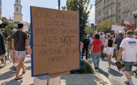 A demonstrator at a march on Sept. 6, 2025, protesting the Trump administration’s federalization of law enforcement and deployment of National Guard troops in Washington, D.C., held a sign on 16th Street NW defending local moped food delivery drivers. 
(Ashley Murray / States Newsroom)