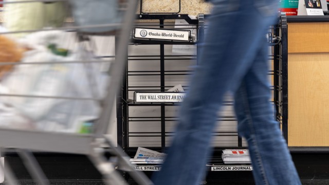 A grocery store shopper passes by a newsstand in Omaha where daily papers sit for sale on Oct. 8, 2025. The Omaha World-Herald and the Lincoln Journal-Star will no longer print a Monday edition starting in early November. 
(Naomi Delkamiller / The Midwest Newsroom)