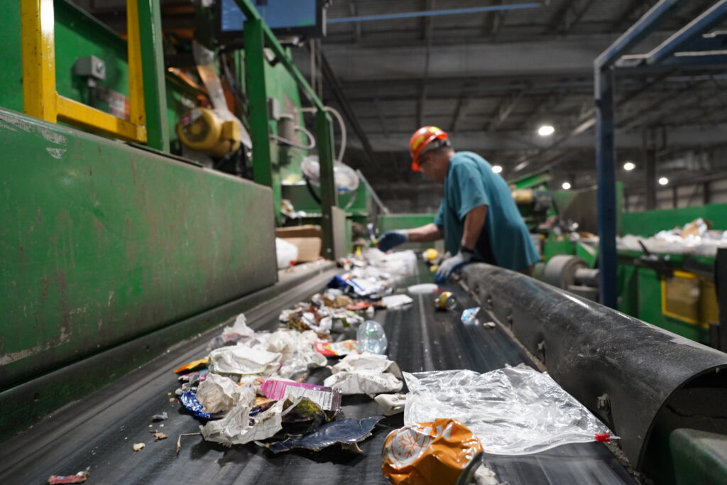 A worker at First Star Recycling, a material recovery facility in South Omaha, sorts out recyclables on the conveyor belt. Omaha’s recyclables start their journey to different markets at the facility, the city’s contractor.<br /> (Yanqi Xu / Flatwater Free Press)