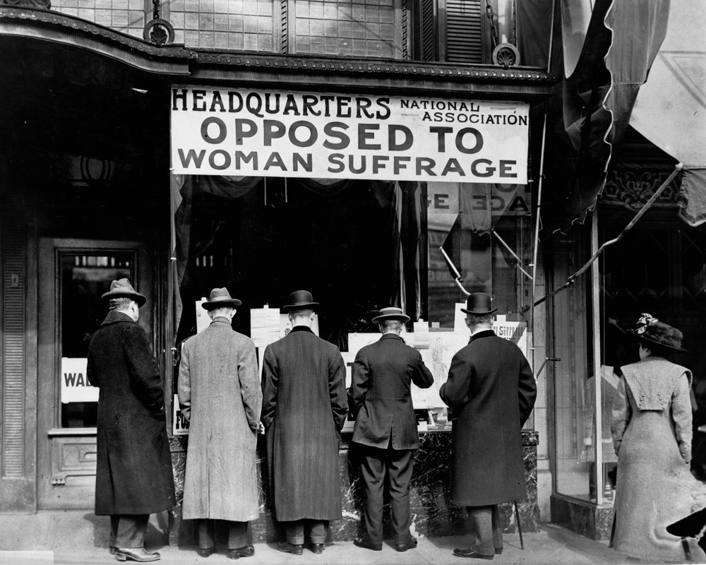 In this circa 1911 photo made available by the Library of Congress, men look at materials posted in the window of the National Anti-Suffrage Association headquarters in the United States. (Harris &amp; Ewing/Library of Congress via AP)