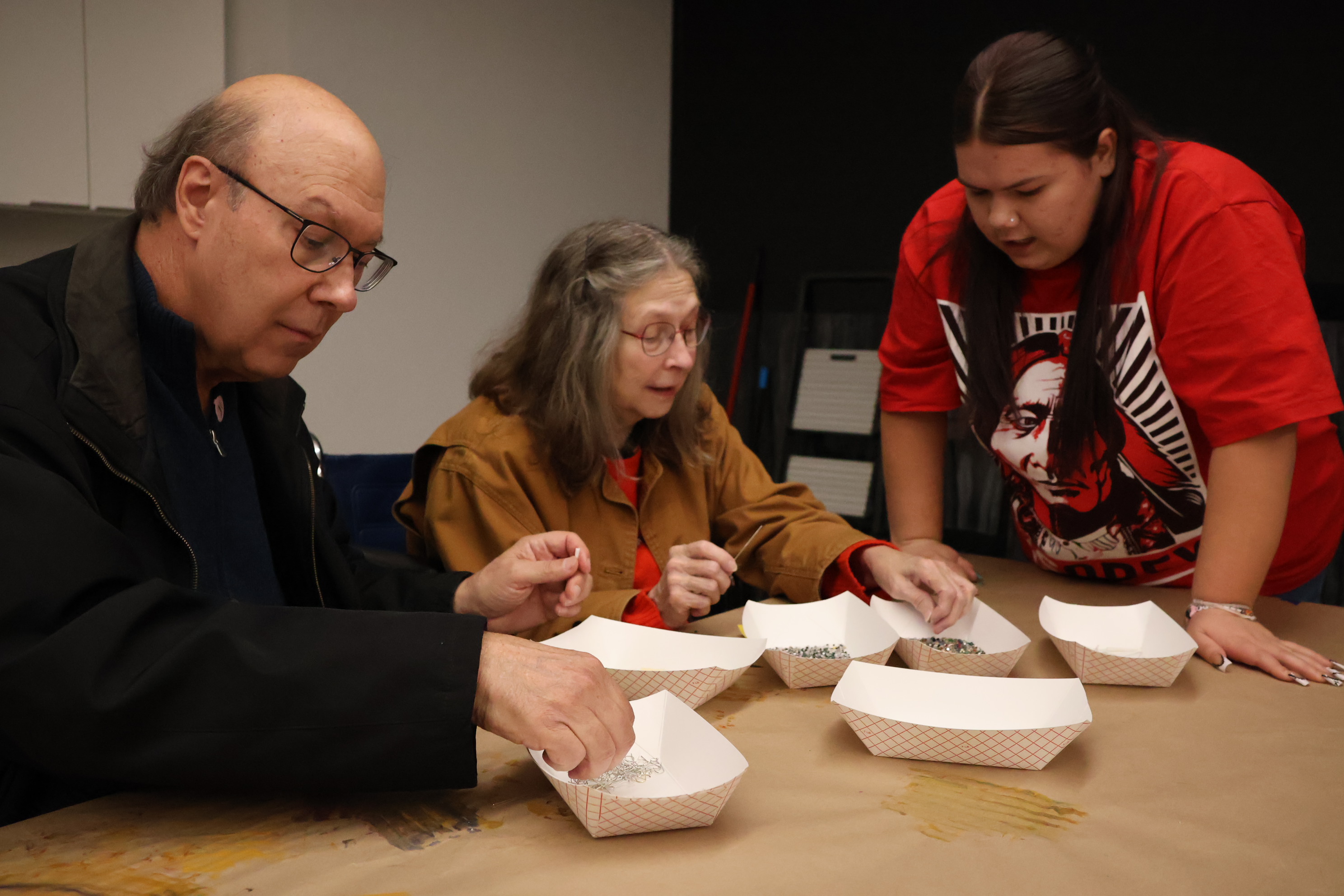 A couple learn how to do beadwork by a Bluebird volunteer during a presentation at Joslyn Art Museum in Omaha.<br />(Tim Trudell / The Daily Record)