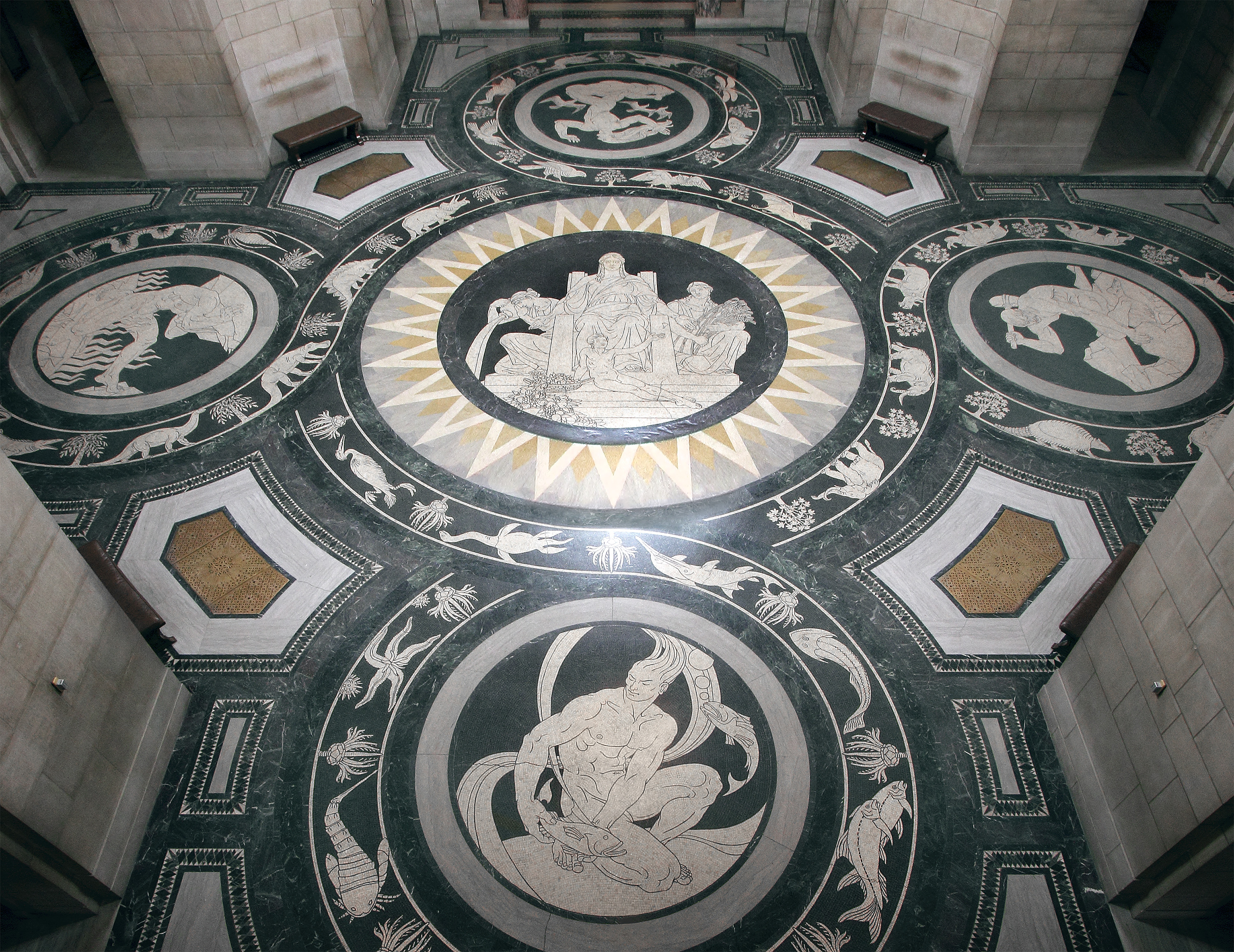 The rotunda theme “Virtues of the State,” features eight winged figures in the dome.<br />The large marble mosaic, in the center of the rotunda floor, is “Earth as the Life-Giver” surrounded by symbols of Water, Fire, Air and Soil, bordered by elements of Nebraska’s prehistoric life.<br />(International Hildreth Meière Association)