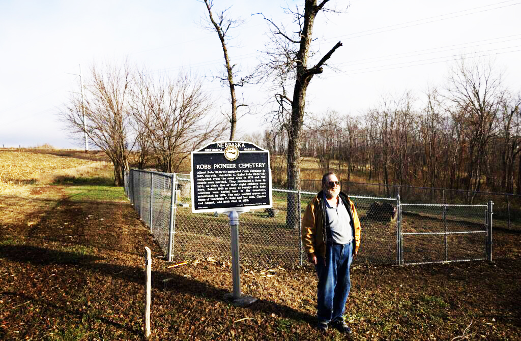 Ernest Kobs stands next to the state historical marker for Kobs Pioneer Cemetery in Glacier Creek Preserve south of Bennington. Kobs’ great-grandparents bought a farm in the area in the 1870s and established the family cemetery.<br />(Rebecca S. Gratz / Flatwater Free Press)