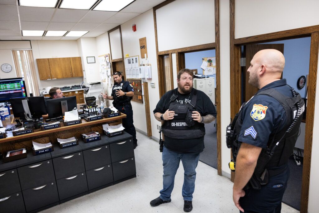 Mental health co-responder Jon Thomsen (left) chats with Sgt. John Brady in the Fremont Police Department. Not all officers are comfortable navigating mental health crises, Brady said. Thomsen, who has struggled with mental health and addiction, is able to relate to people in crisis and deescalate the situations.<br /> (Rebecca S. Gratz / Flatwater Free Press)