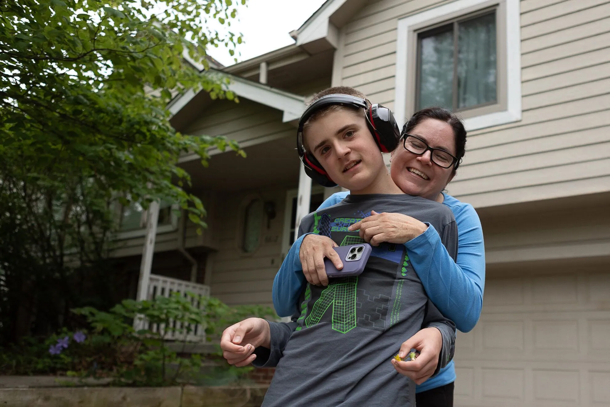 Teddy Gleason leans into a hug with his mother Angela outside their northwest Omaha home on Friday, May 23, 2025. Teddy, 13, will start eighth grade at Omaha’s Davis Middle School in the fall.<br />(Liz McCue / Flatwater Free Press)