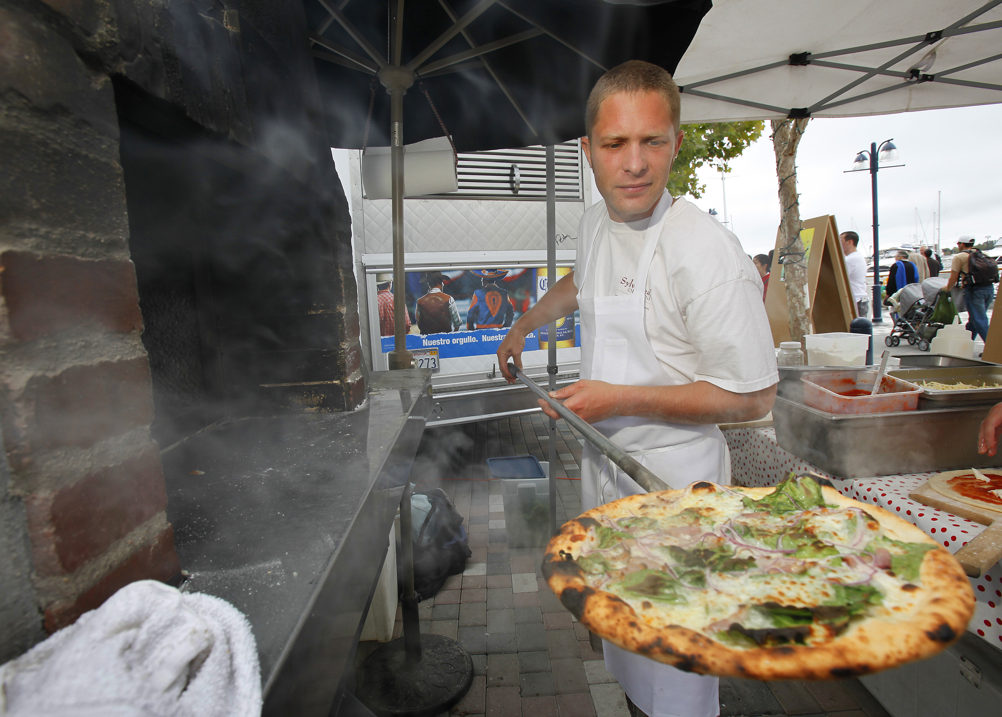 Joel Baecker, owner of Pizza Politana removing an organic pizza that uses seasonal ingredients that come directly from local farmers and artisan producers from authentic Neapolitan wood-fired oven during the Eat Real Festival in Oakland, Calif. The Eat Real Festival, a celebration of sustainable street food, announces a schedule showcasing local talent and rising stars of the Bay Area sustainable food movement.<br />(Tony Avelar / AP Photo)