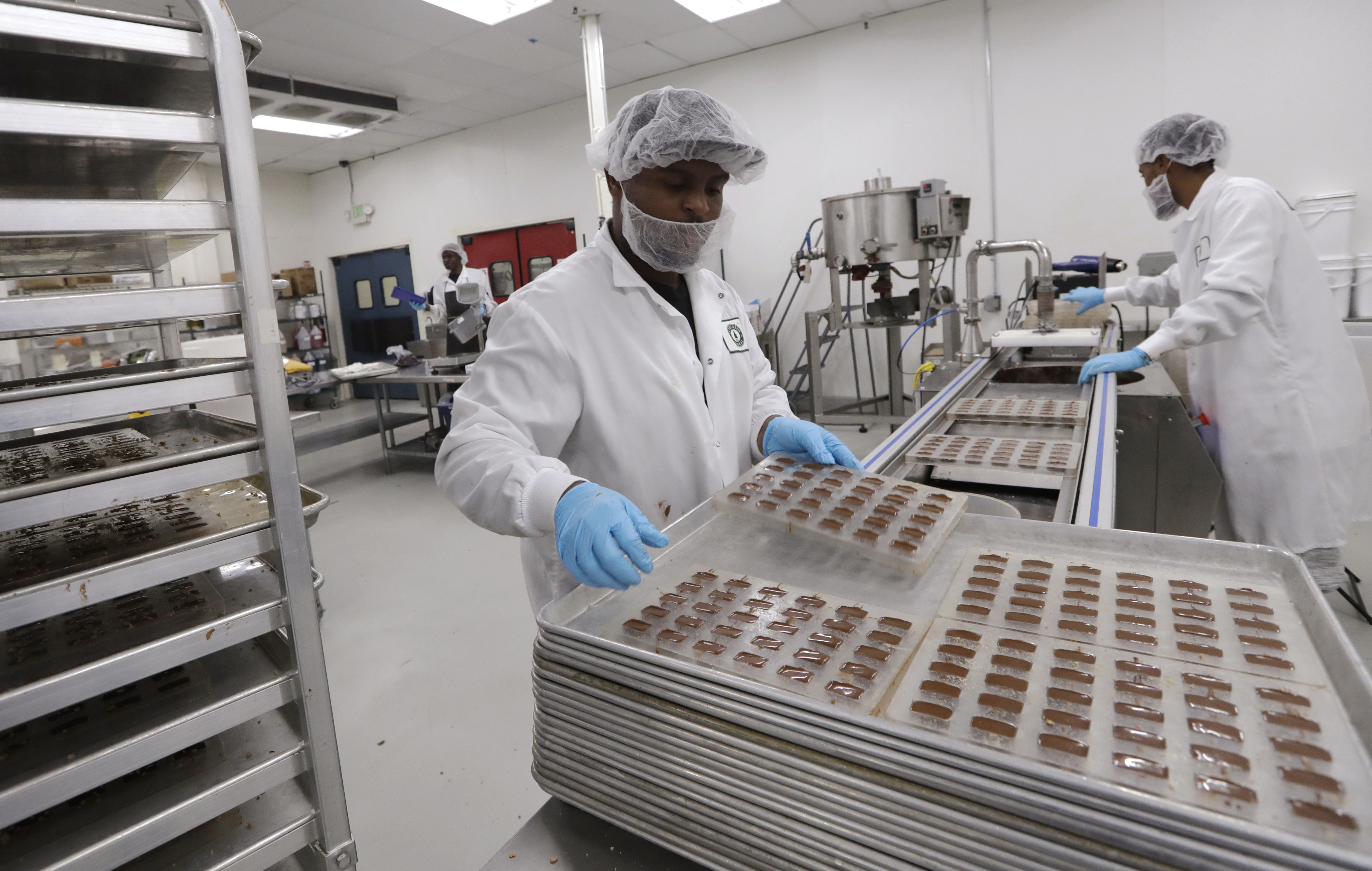 Michael Tyus (left) and Alem Berhane make cannabis-infused chocolate toffee candies at Evergreen Herbal, Wednesday, July 24, 2019, in Seattle.<br />(Elaine Thompson / AP Photo)