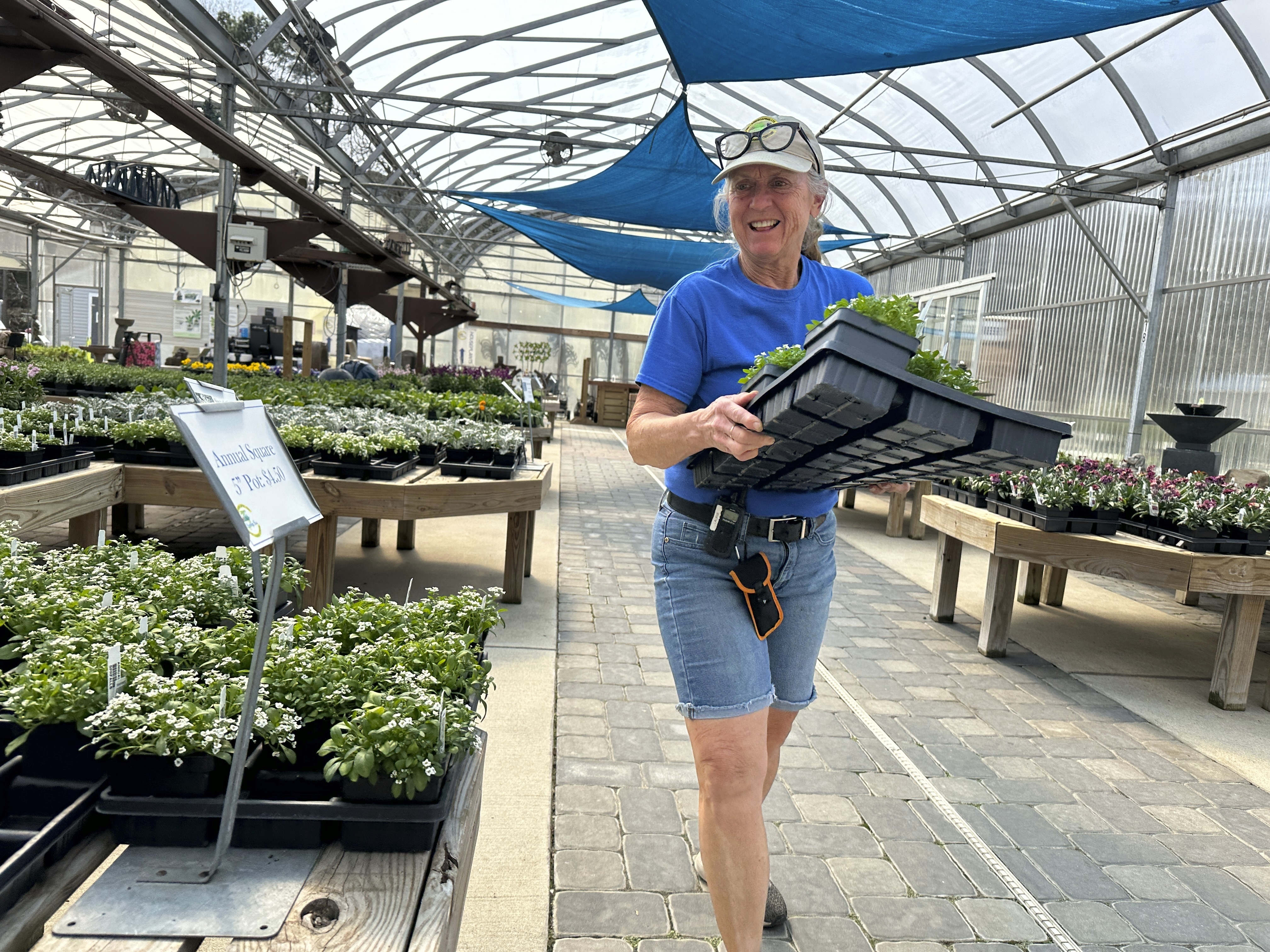 An employee carries a tray of plants at East Coast Garden Center, March 13, 2024 in Millsboro, Del. Garden centers enjoyed a pandemic boom, particularly with millennials, as people looked for outdoor activities during lockdowns. Now, garden centers are hoping to keep that interest up, even as they deal with higher costs, a tough hiring environment and ever more volatile weather.<br />(Tassanee Vejpongsa / AP Photo)