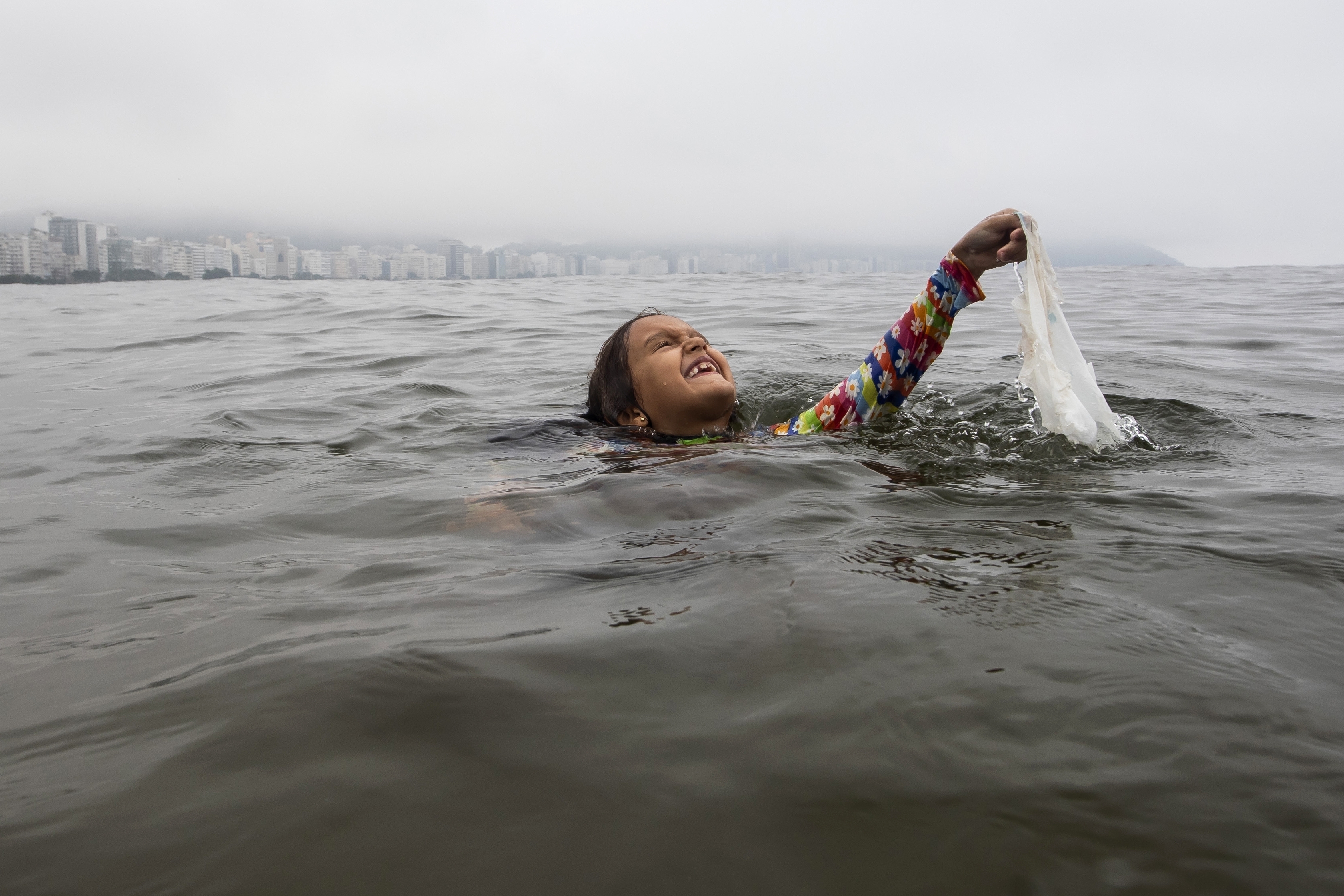 Nina Gomes recovers a discarded plastic bag from ocean waters, near Copacabana beach in Rio de Janeiro, Brazil, March 19, 2024.<br />(Bruna Prado / AP Photo)