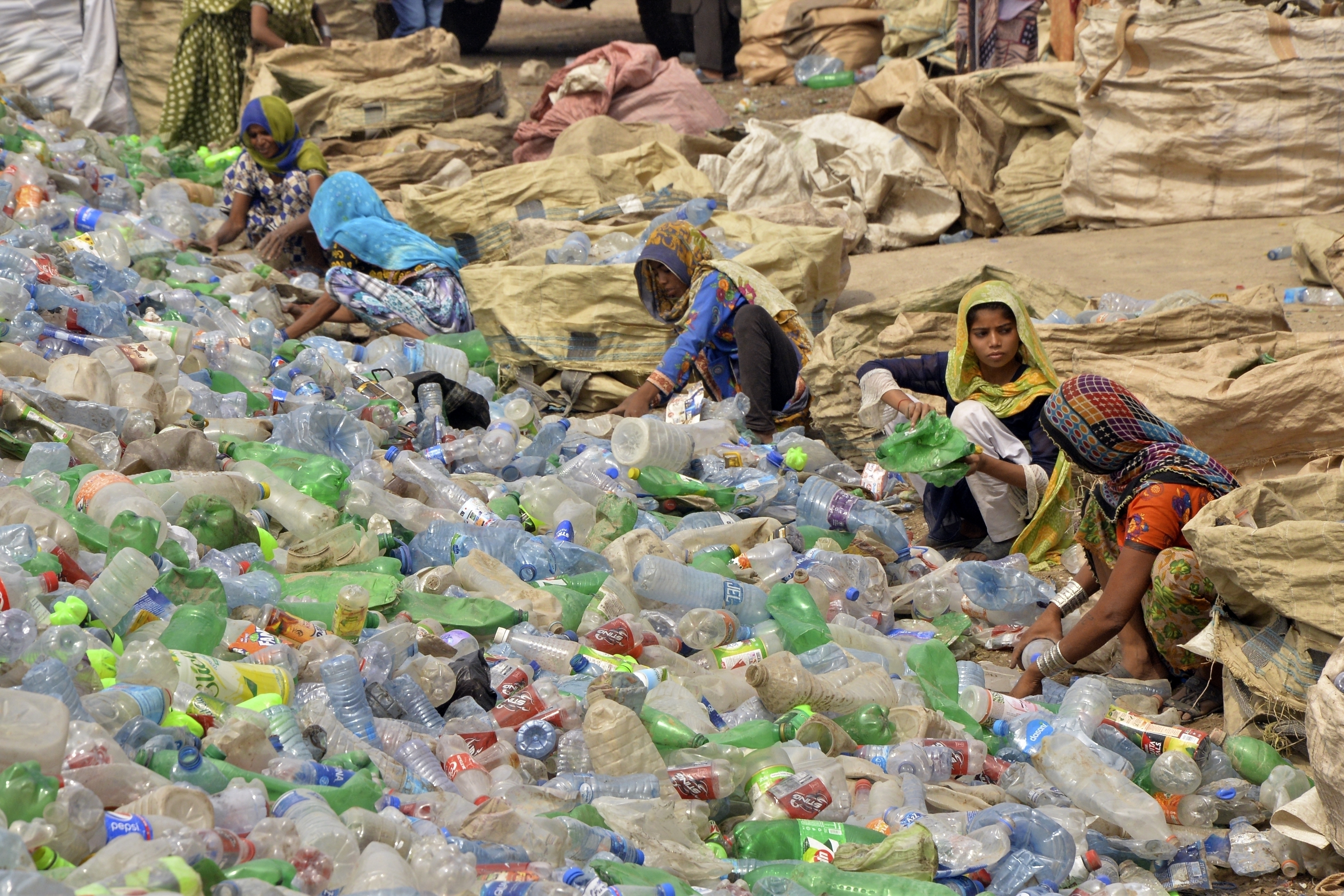 Pakistani laborers, mostly women, sort through empty bottles at a plastic recycling factory in Hyderabad, Pakistan, April 30, 2023.<br />(Pervez Masih / AP Photo)