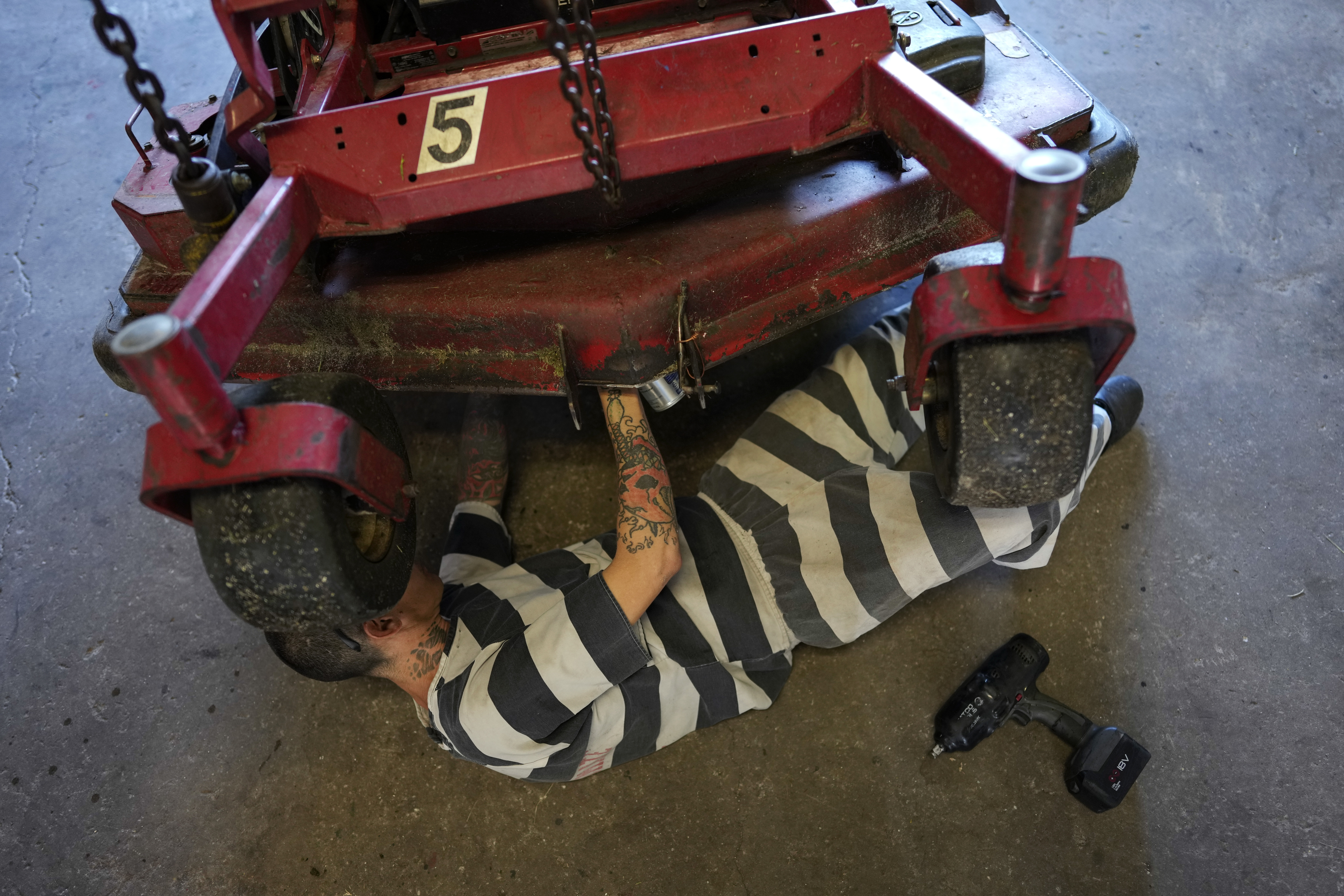 Diesel mechanic Johnny Reyes, a former gang member who says he is serving a 364 day sentence in the Brevard County jail for burglary and violating probation, does maintenance on landscaping equiptment in a workshop at the Sheriff’s Work Farm.<br />(Rebecca Blackwell / AP Photo)