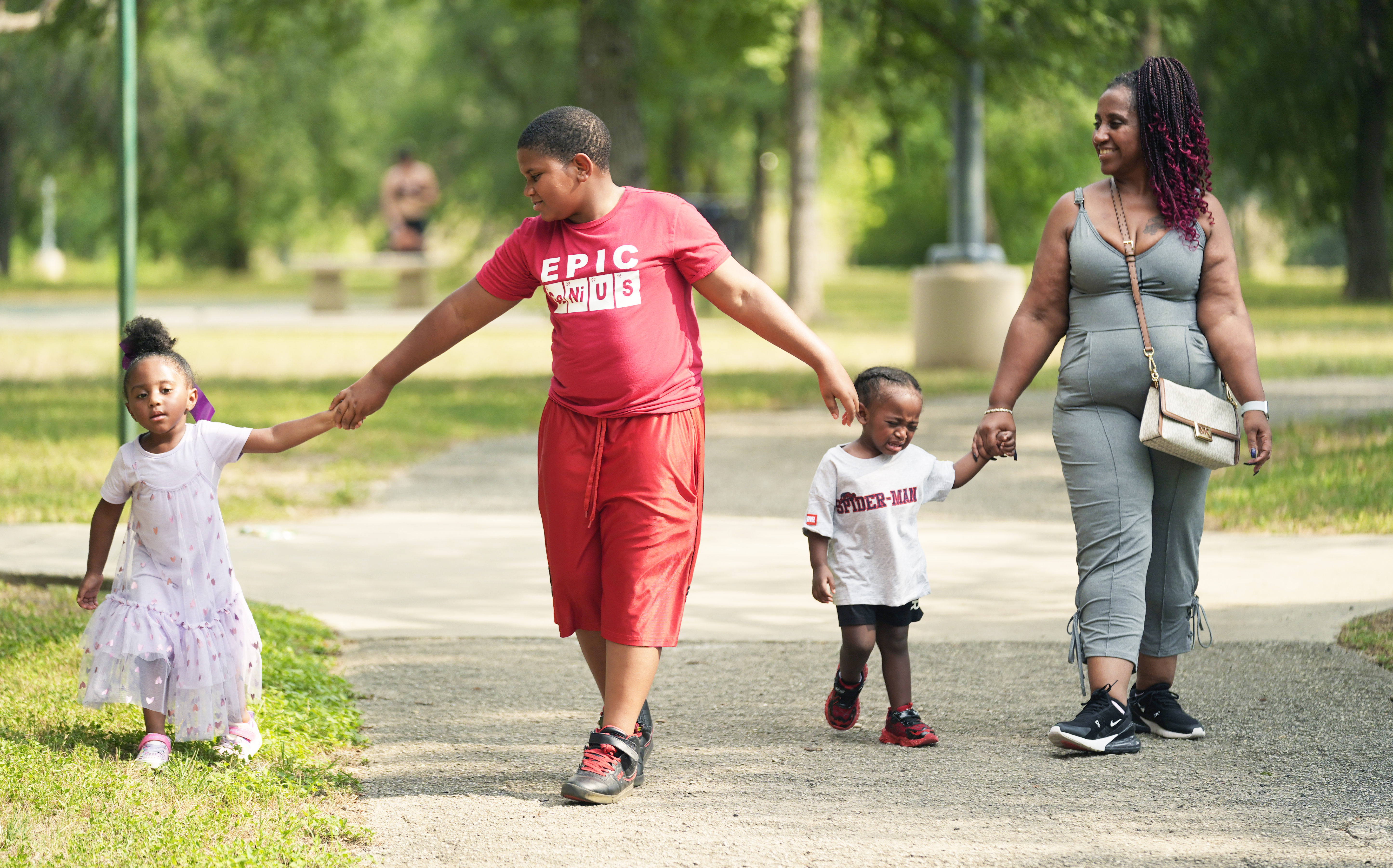Tamika Davis (right) walks through MLK Park with three of her children (from left) Shanara, 3, Matthew, 11, and Lionel Jr., 2, in San Antonio, Thursday, May 30, 2024. Davis said friends and family watched her kids for most of her doctor visits during treatment last year for colon cancer. But she couldn&#039;t afford additional childcare, and she didn&#039;t know where to look for assistance.<br />(Eric Gay / AP Photo)