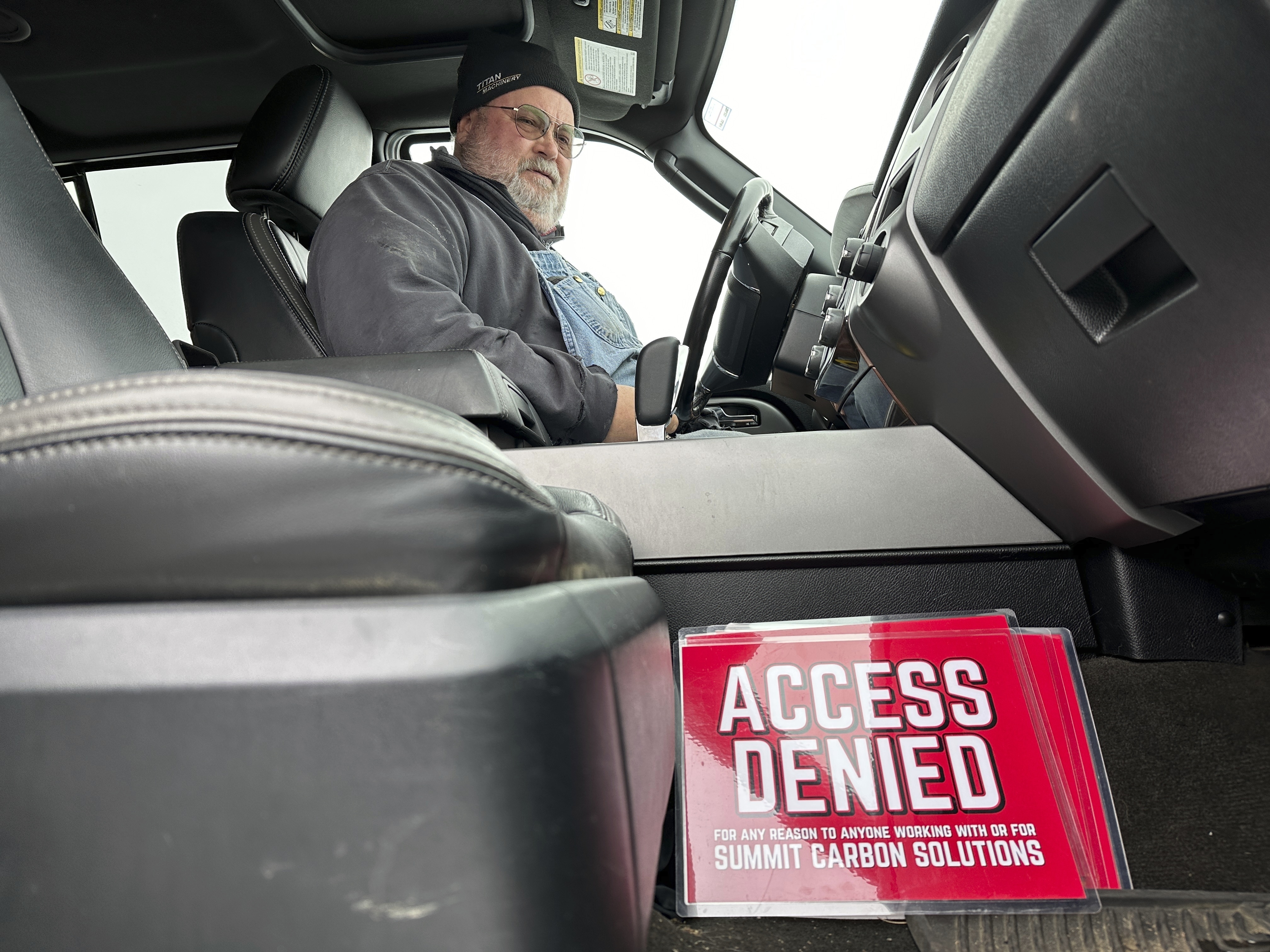 Dan McLean looks down at a sign that reads &quot;Access denied for any reason to anyone working with or for Summit Carbon Solutions,&quot; in his truck on Wednesday, March 6, 2024, on his farm near Menoken, N.D. Summit Carbon Solutions has proposed a multistate carbon dioxide pipeline that would bury CO2 deep underground in North Dakota. The project has drawn opposition from many Midwestern landowners.<br />(Jack Dura / AP Photo)