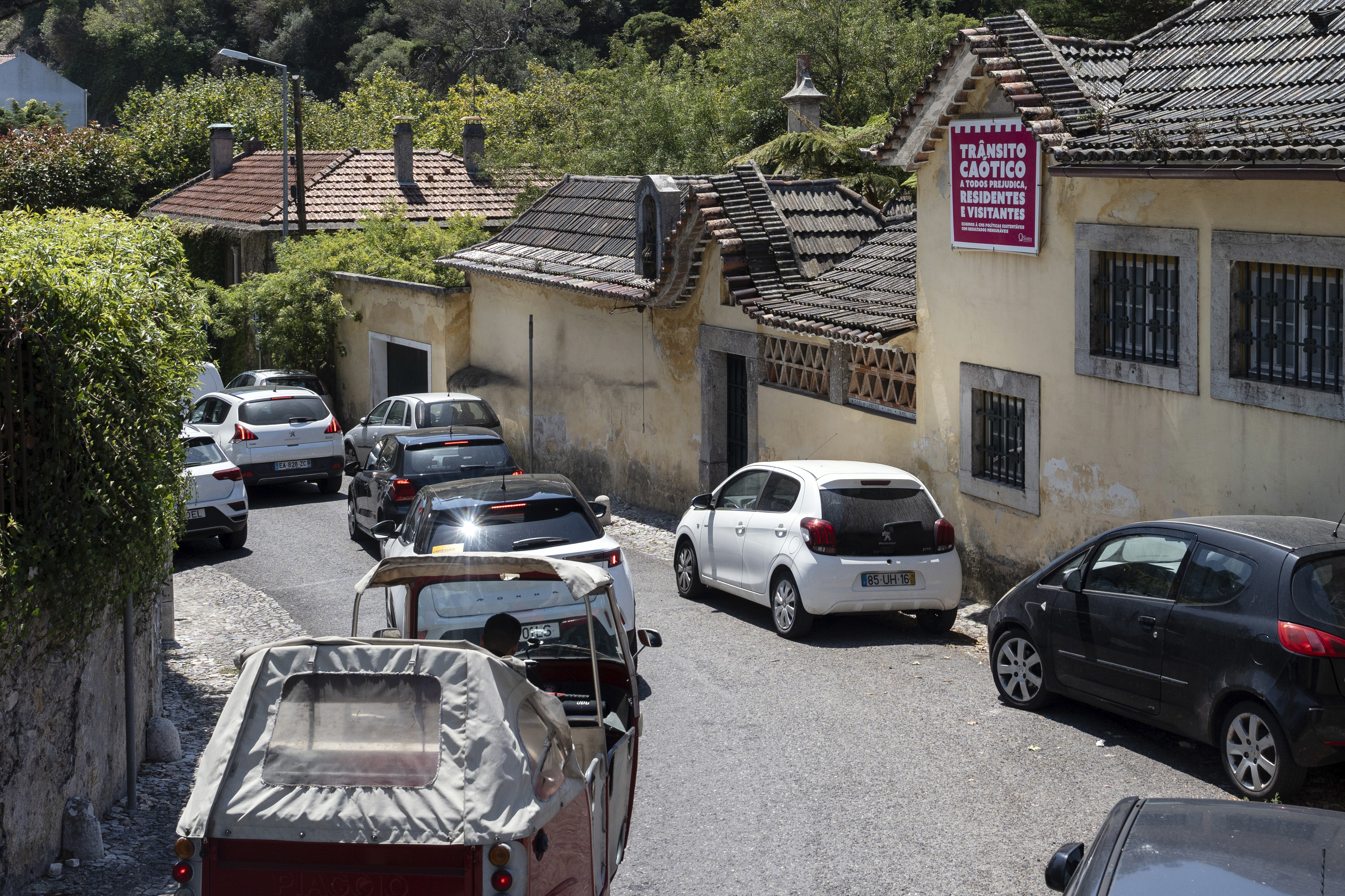 Traffic crawls through a narrow street where a poster on the wall of a house reads in Portuguese &quot;Chaotic traffic harms everyone, residents and visitors&quot;, in Sintra, Portugal, Friday, Aug. 9, 2024.<br />(Ana Brigida / AP Photo)