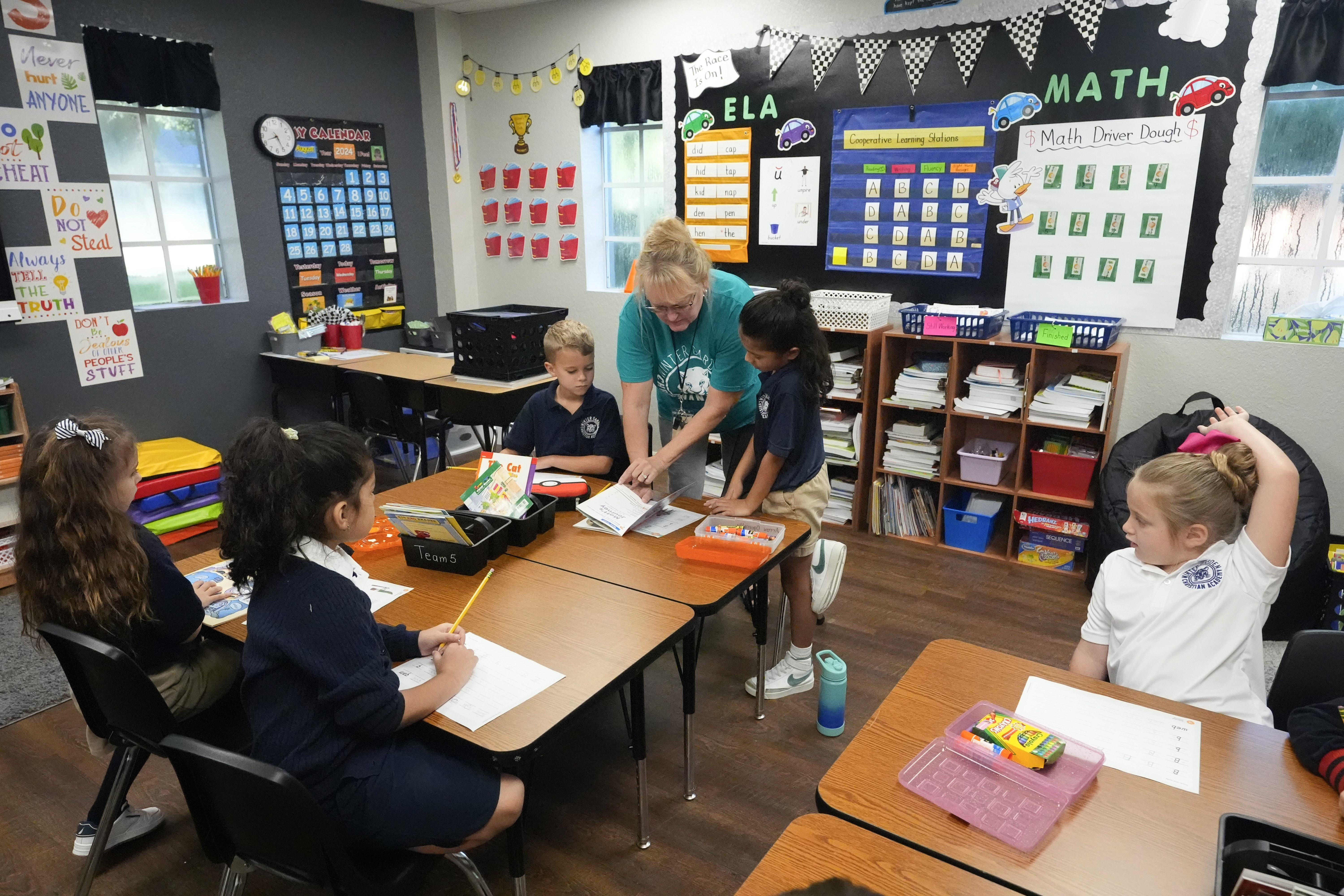 First grade teacher Sharon Parsons (back center) helps her students with a lesson at the Winter Garden Christian Academy Thursday, Aug. 29, 2024, in Winter Garden, Fla.<br /> (John Raoux / AP Photo)