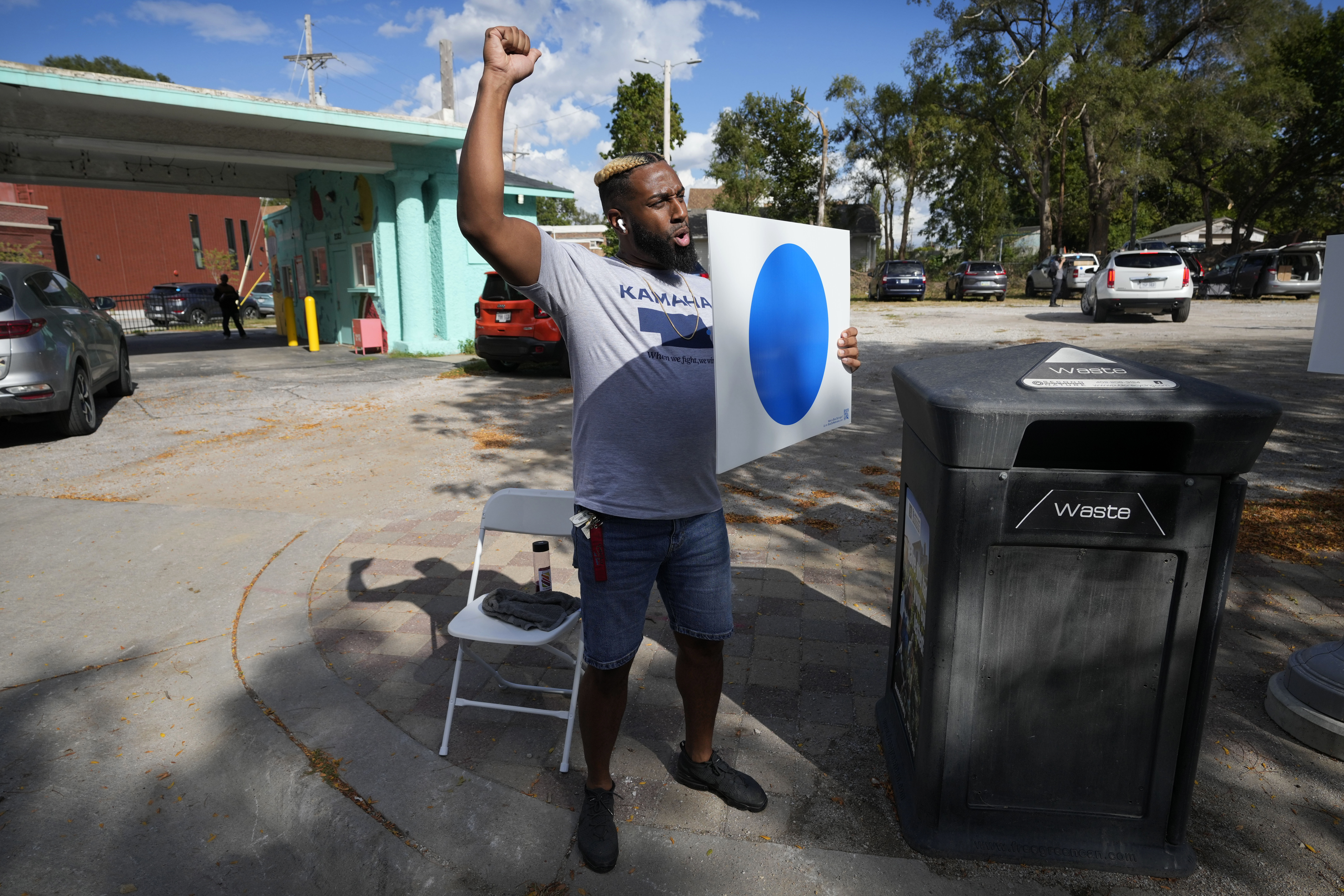 Shawn Steward reacts to a passing vehicle during a blue dot campaign sign get-together, Tuesday, Sept. 24, 2024, in Omaha, Neb. The blue dot signs, spotted throughout Omaha, represent Democratic-voting households in a state surrounded by Republican red.<br />(Charlie Neibergall / AP Photo)
