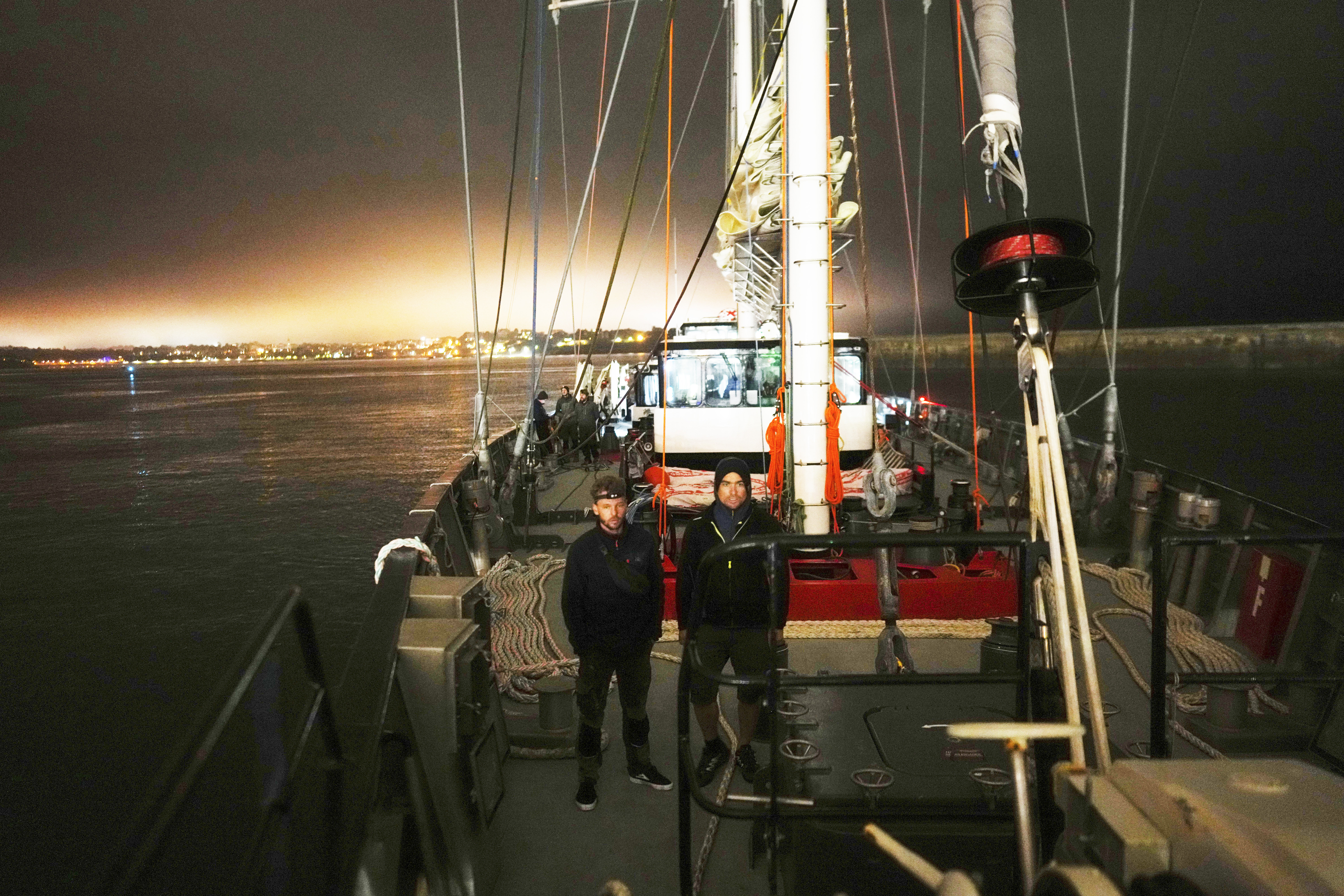Sailors Tim Padellec (left) and Charles Mirassou stand on the deck of the sailboat &#039;Grain de Sail II&#039; as he sails off Saint Malo, western France, Nov. 6, 2024.<br />(Thibault Camus / AP Photo)
