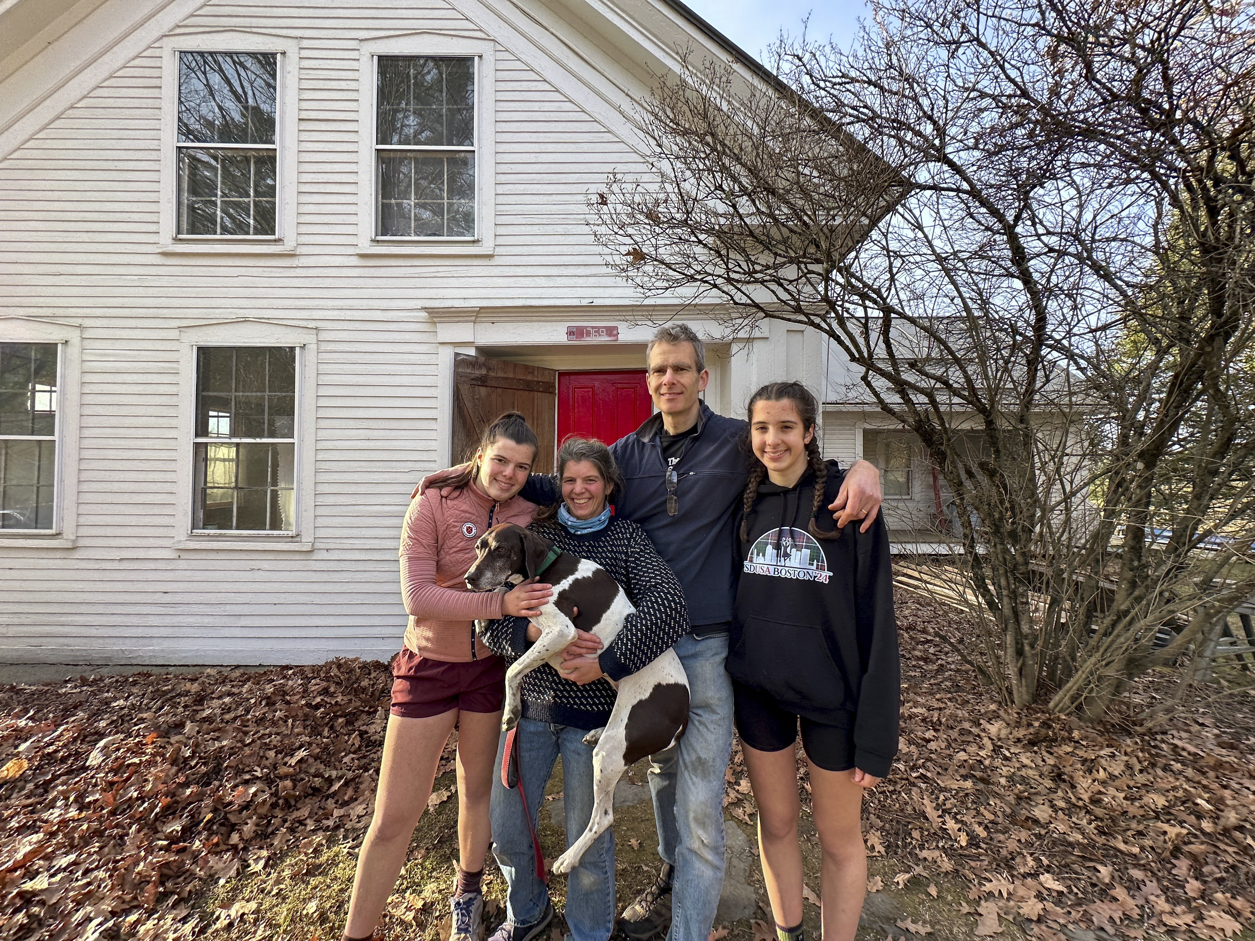 The Mackenzies (from left to right) Lila, Jenny, John, Kate and their dog Hester pose in front of their new house in Craftsbury, Vt. on Nov. 17, 2024.<br />(Lisa Rathke / AP Photo)