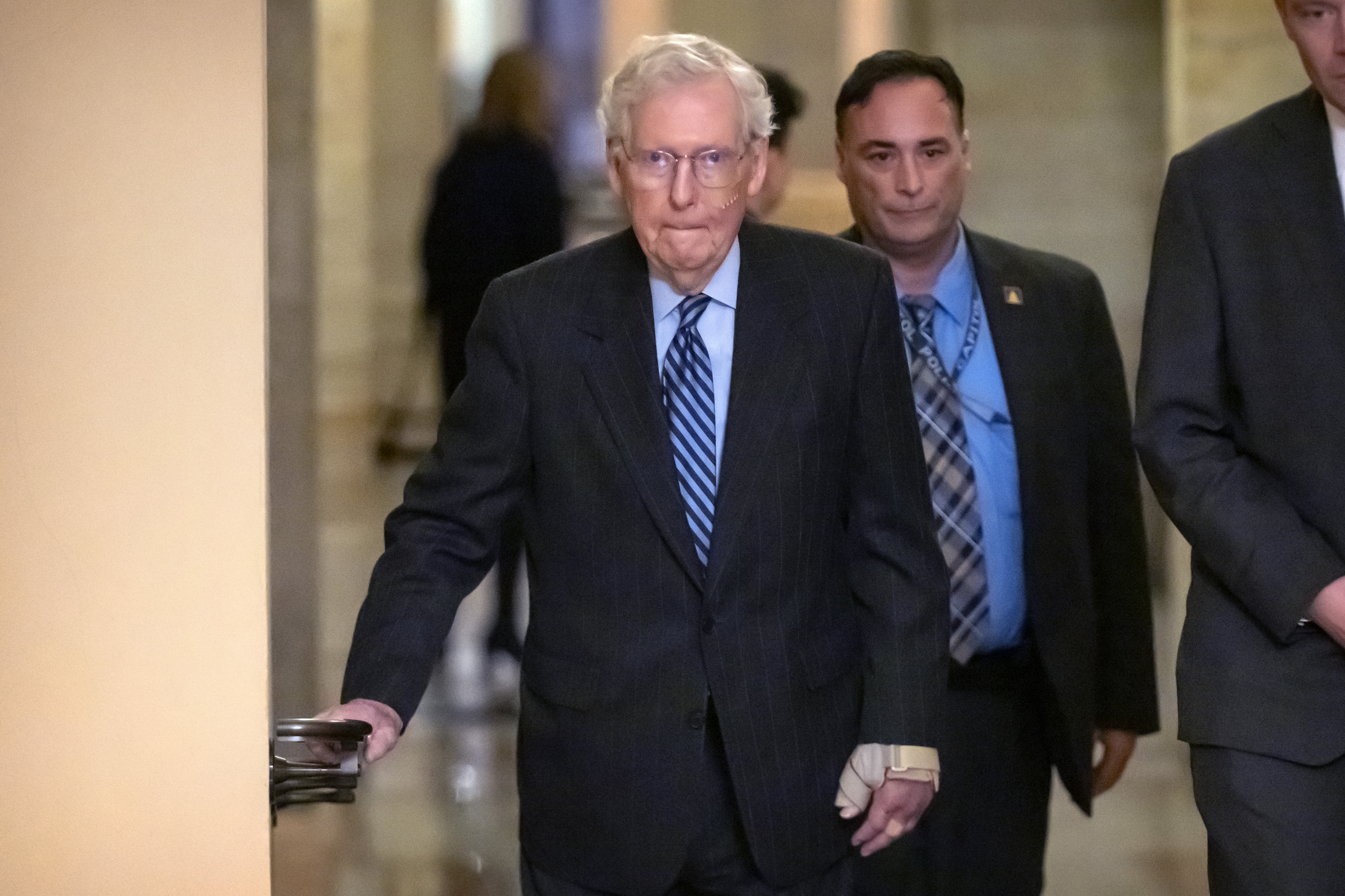 Senate Minority Leader Mitch McConnell of Ky. (left) wears a bandage on his face and wrist as he walks to cast a vote on the Senate floor after falling during a luncheon on Capitol Hill, Tuesday, Dec. 10, 2024, in Washington.<br /> (Mark Schiefelbein / AP Photo)