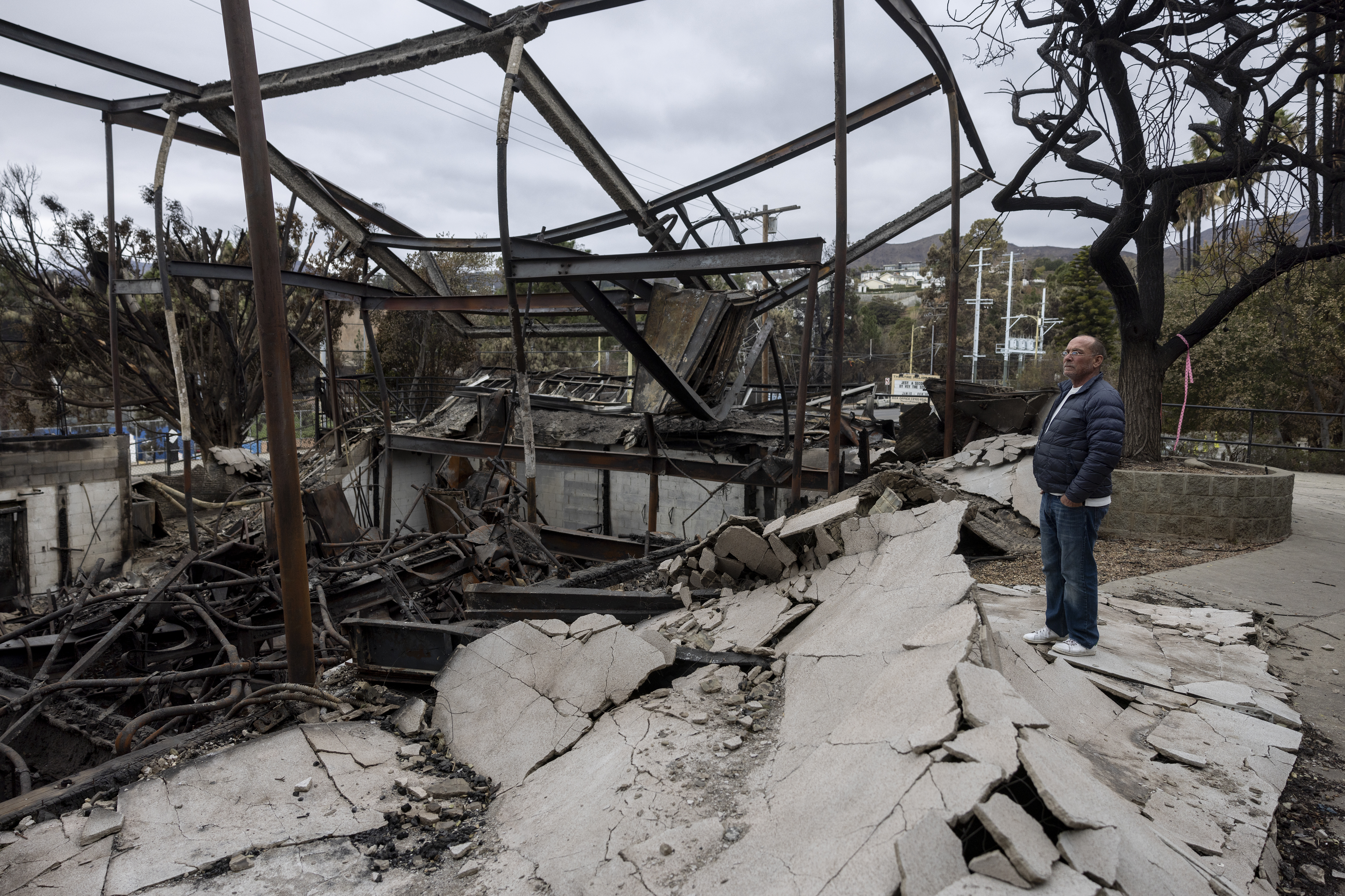 Costume designer for the youth theatre program of the Theatre Palisades, David Montgomery looks at the ruins of the theater destroyed by the Palisades Fire, in the Pacific Palisades neighborhood of Los Angeles, Calif., Saturday, Jan. 25, 2025.<br />(Etienne Laurent / AP Photo)