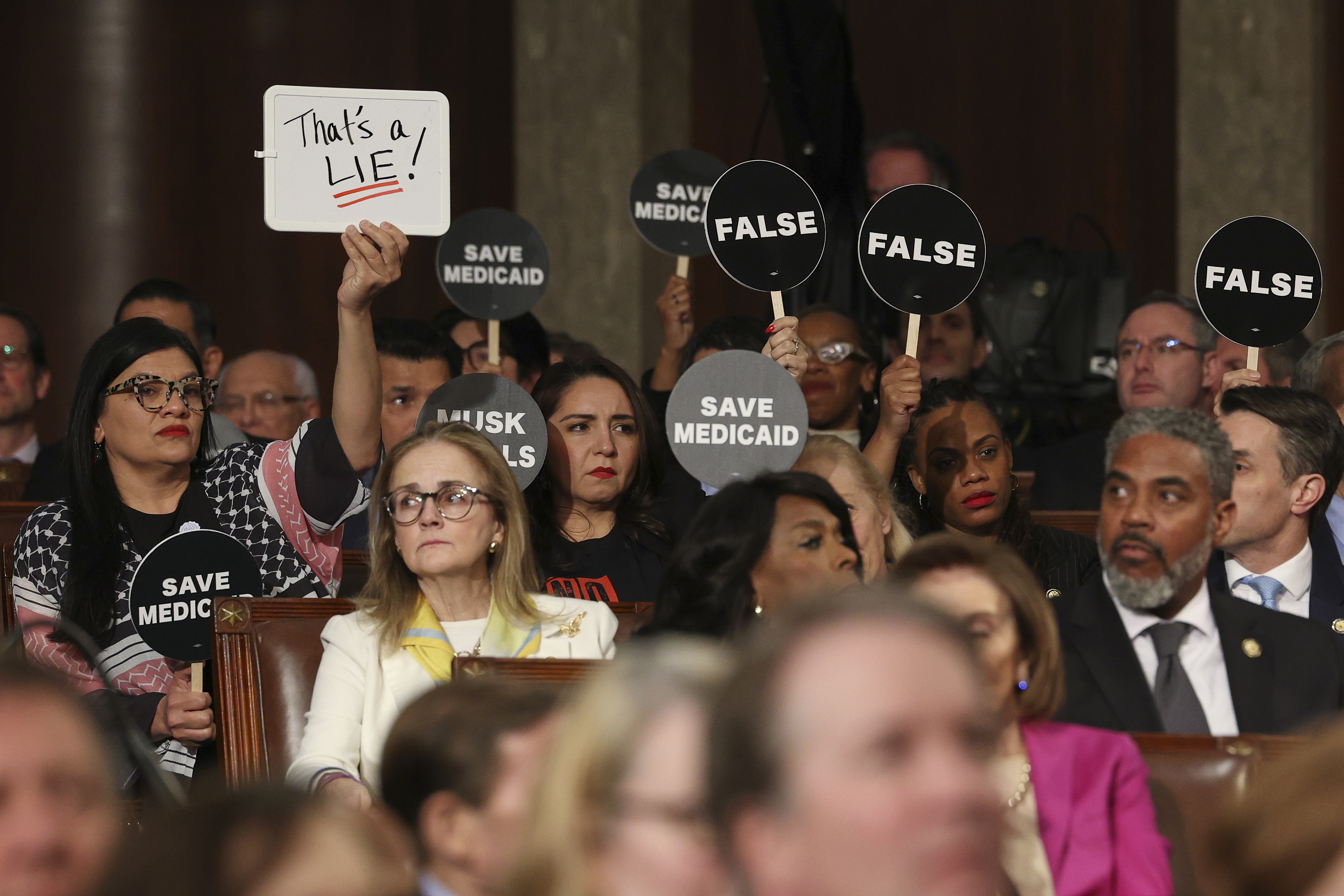 Democrats hold protest signs as President Donald Trump addresses a joint session of Congress at the Capitol in Washington, Tuesday, March 4, 2025.<br />(Win McNamee / Pool Photo via AP)