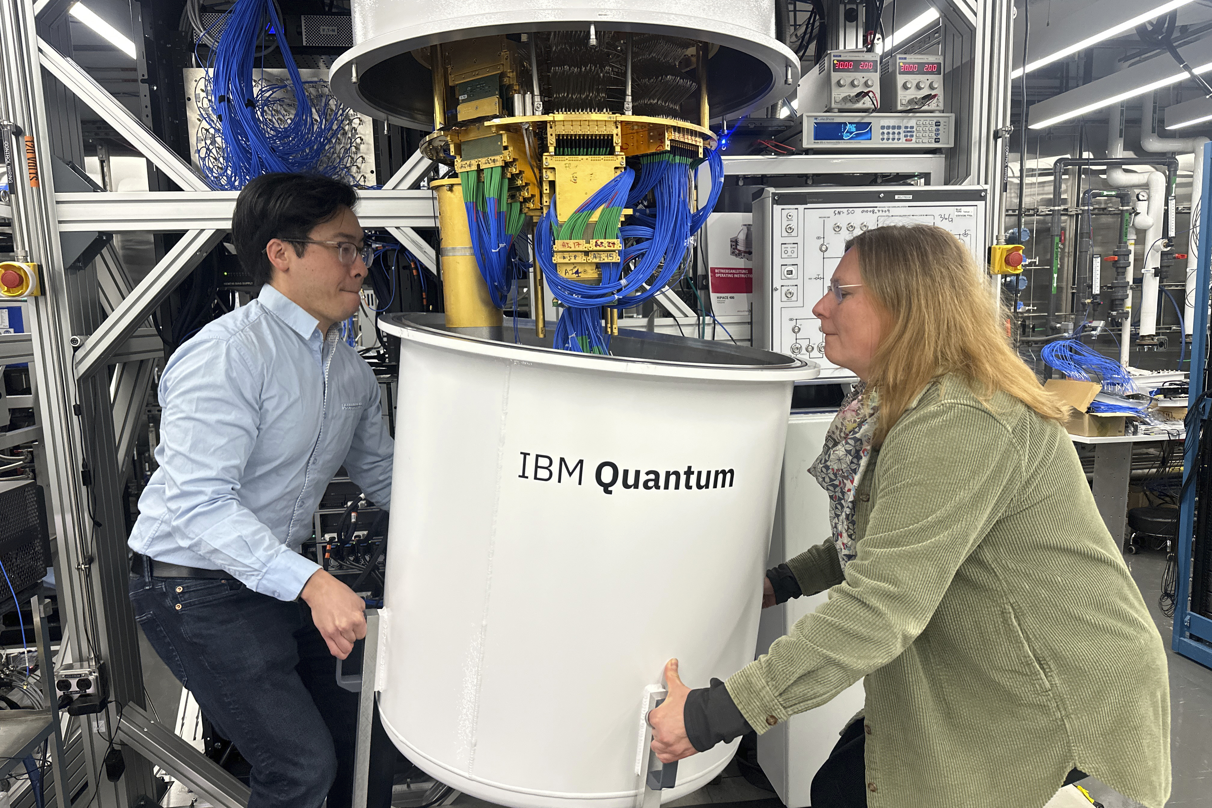 Jerry Chow, IBM Fellow and Director of Quantum Infrastructure (left) and Daniela Bogorin, IBM Quantum Research Engineer, remove the outer chamber from a quantum computer in Yorktown Heights, New York, on Wednesday, March 5, 2025.<br />(Ted Shaffrey / AP Photo)